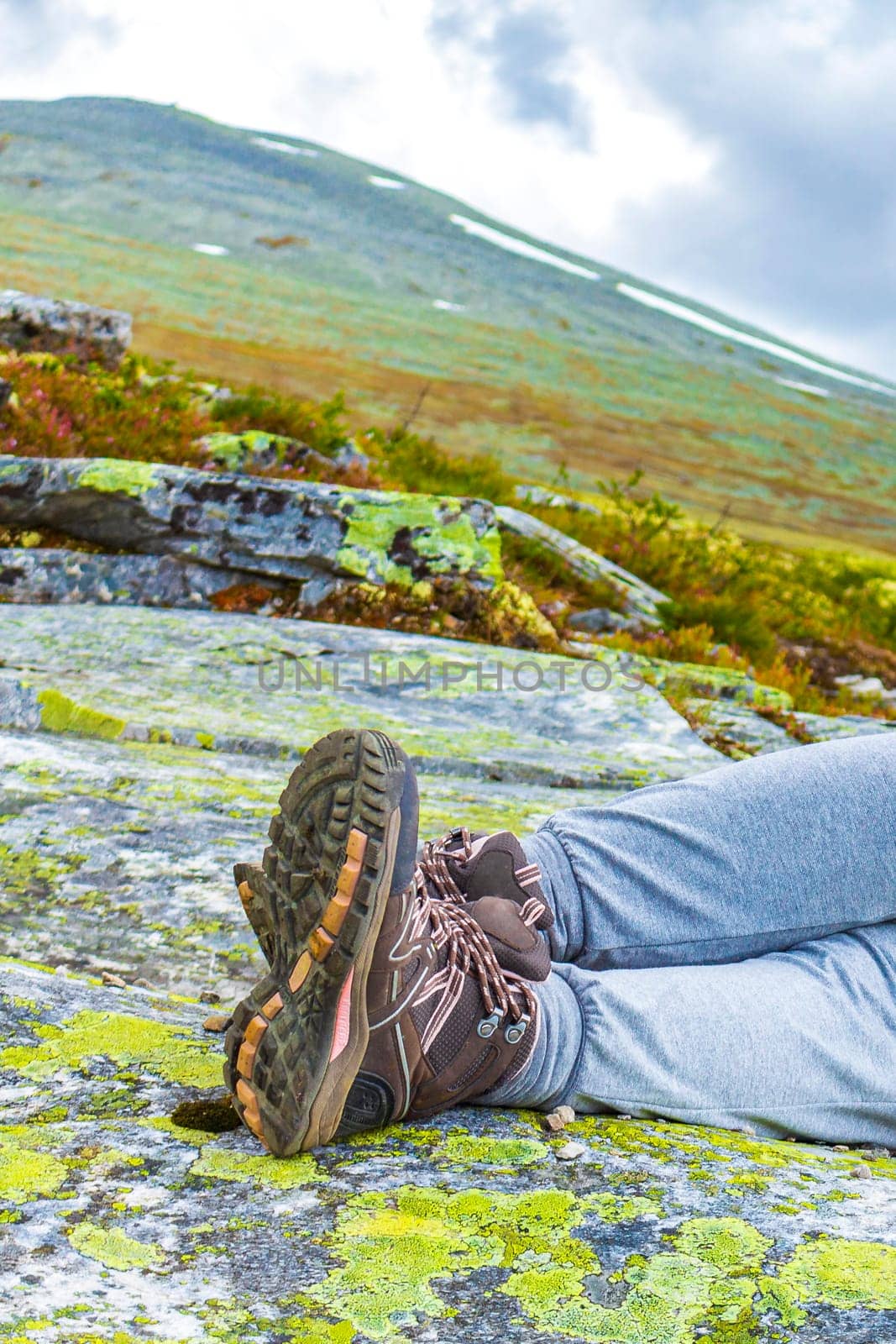 Hiking boots and womens legs on rock mountains in Norway. by Arkadij