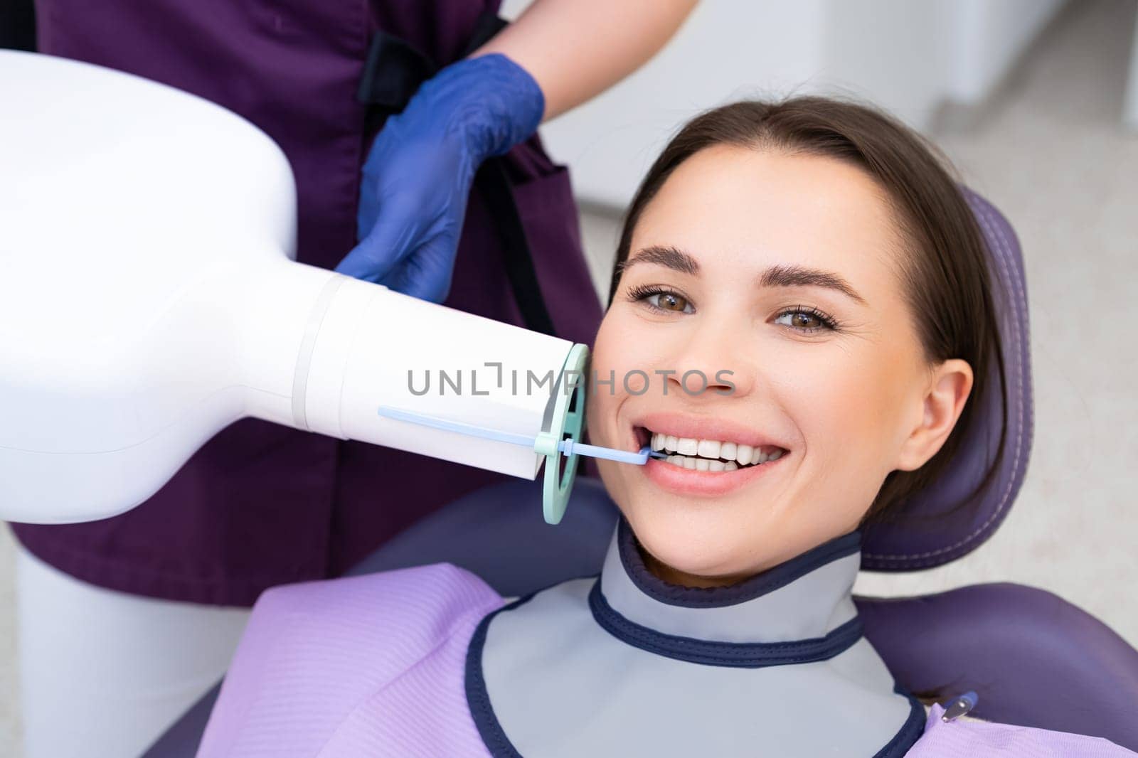 A female patient smiles as she receives a teeth X ray at the dental clinic. by vladimka