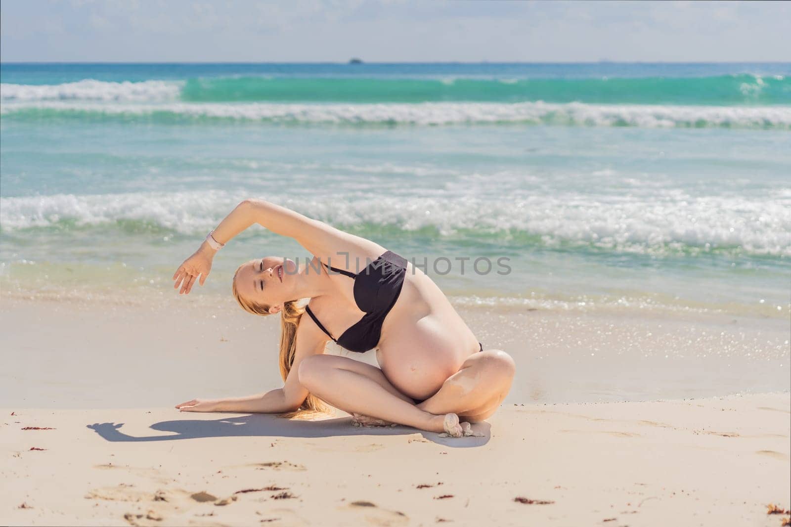 Harmonizing mind and body, a pregnant woman gracefully practices yoga on the beach, embracing the serenity of the seaside for a tranquil and mindful pregnancy experience.