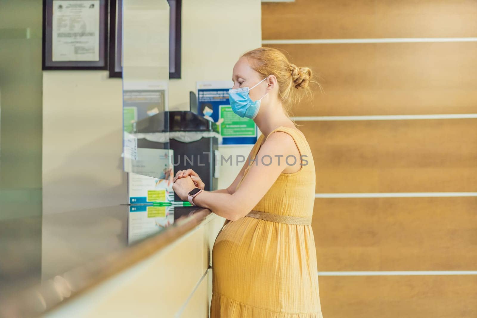 A pregnant woman stands at the hospital reception desk, embarking on a crucial phase of her maternity journey, seeking care and support in a healthcare setting.