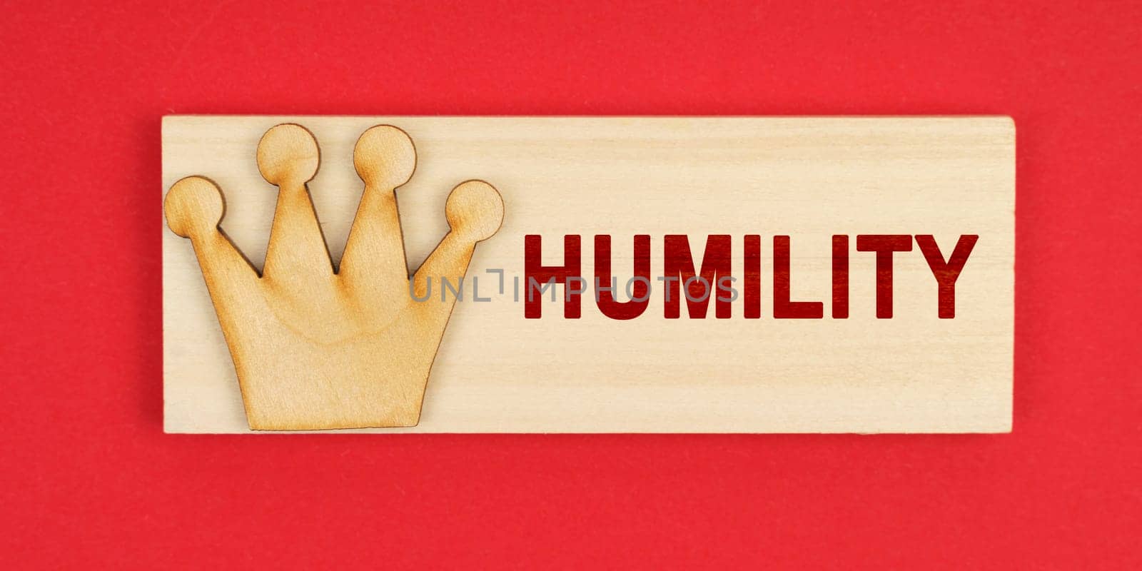 Leader concept. On a red surface there is a wooden block with the inscription - Humility