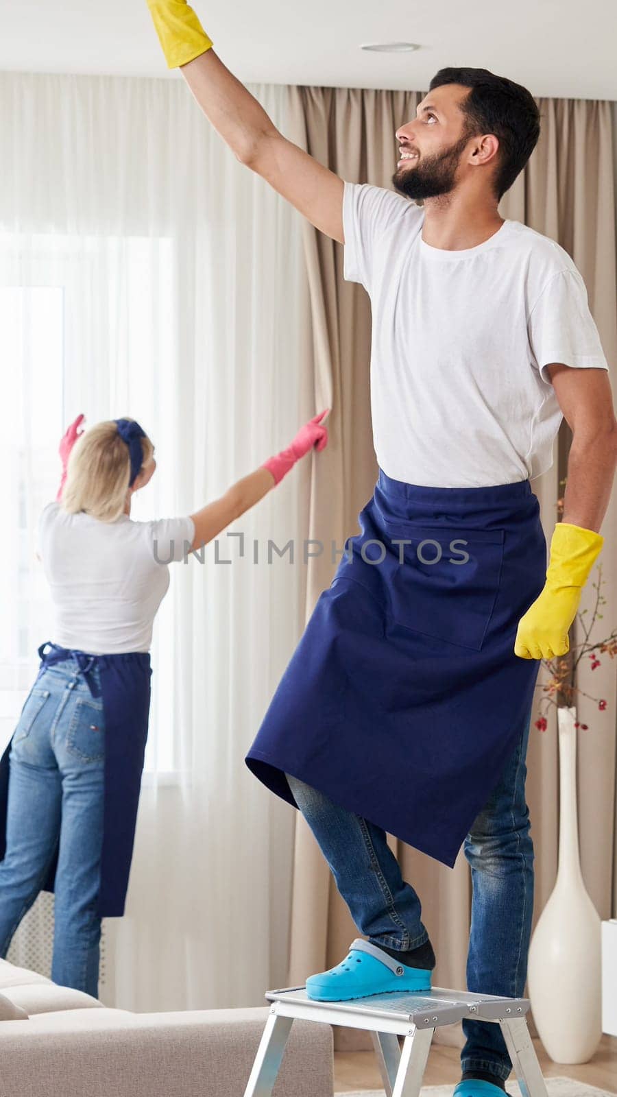 Professional cleaning service team cleans living room in modern apartment by Mariakray