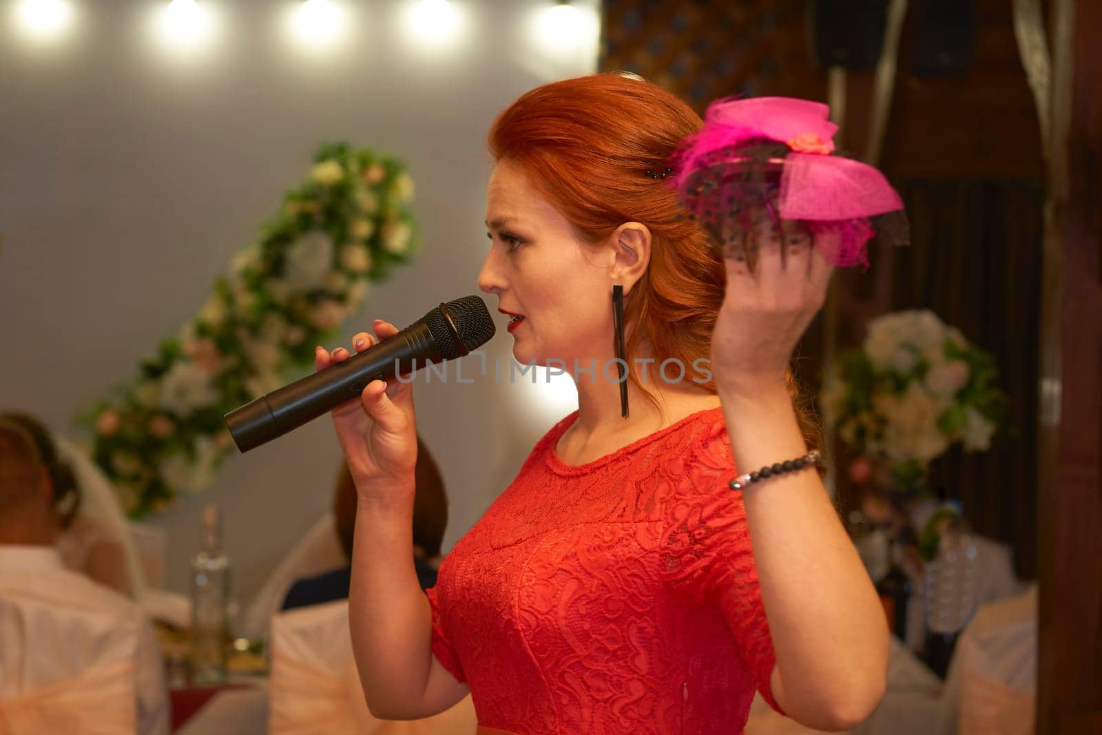 Host of a wedding ceremony. Young woman in red dress with a microphone by jovani68