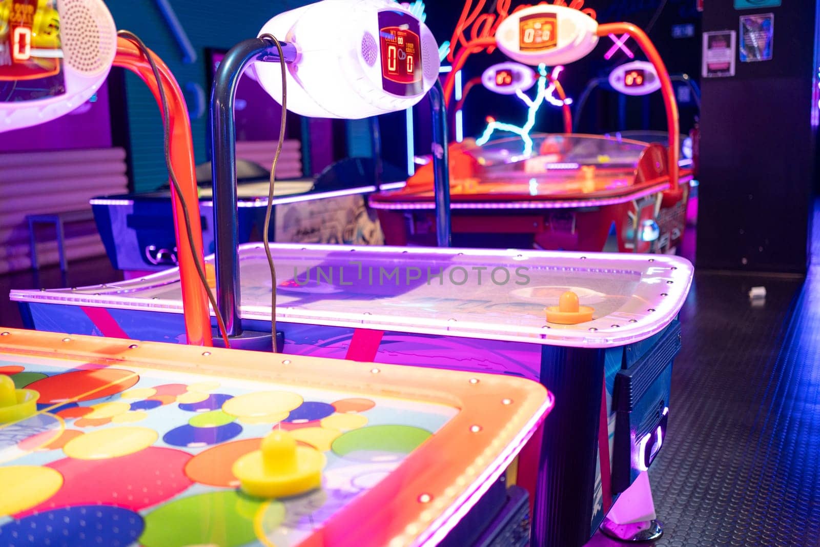 Neon Illuminated air hockey tables in gaming arcade at night by andreonegin
