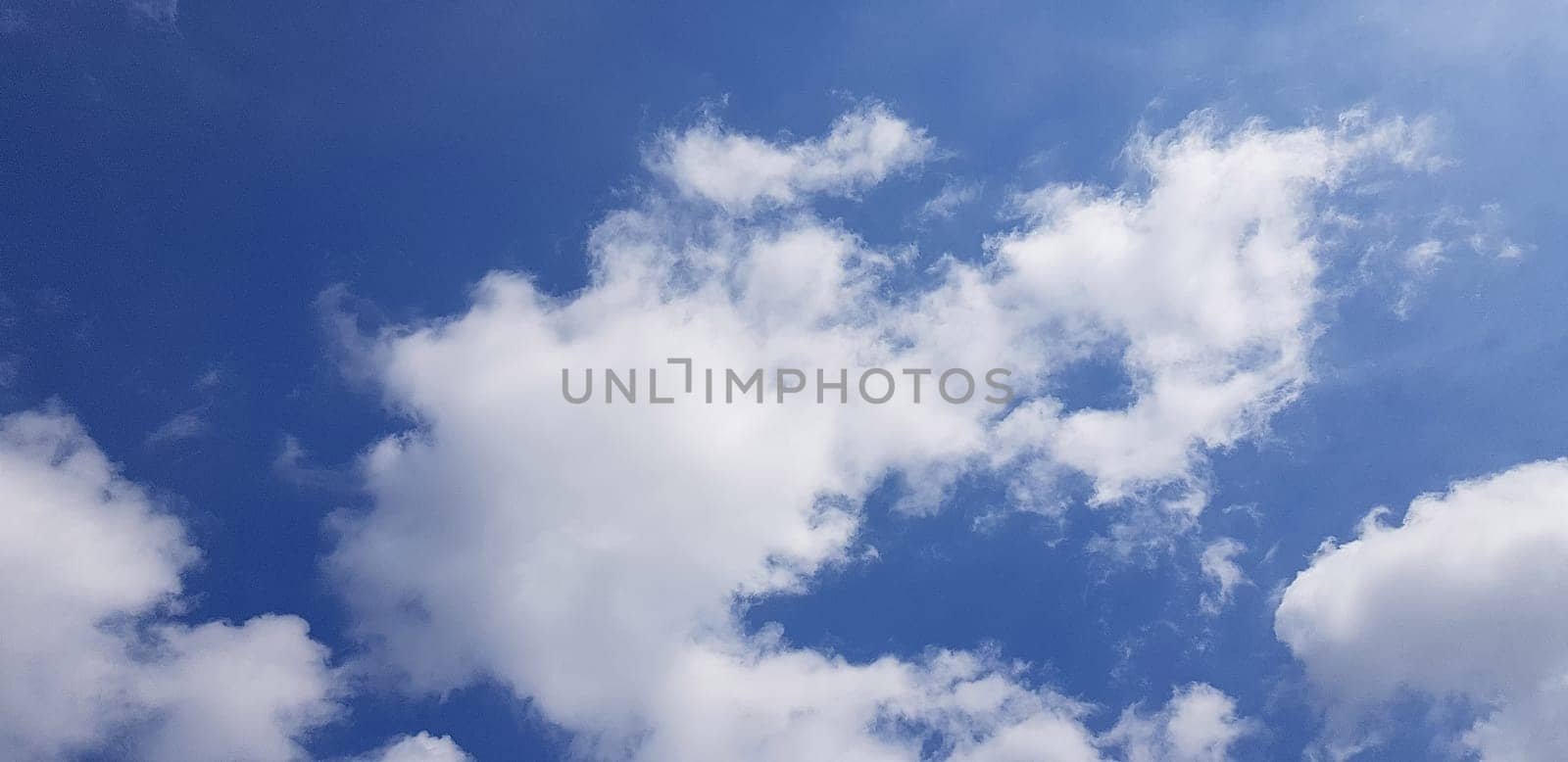 Heavenly white clouds on the blue sky background with the sun appeared perfect for multimedia texture or background by antoksena