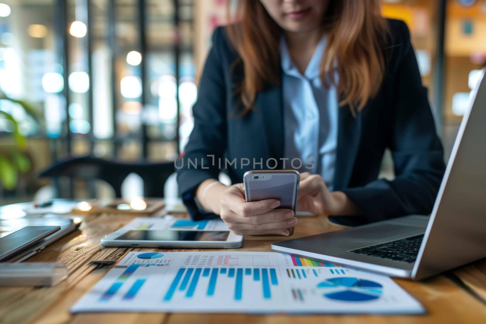 Close up of Businesswoman using smartphone while working on laptop.