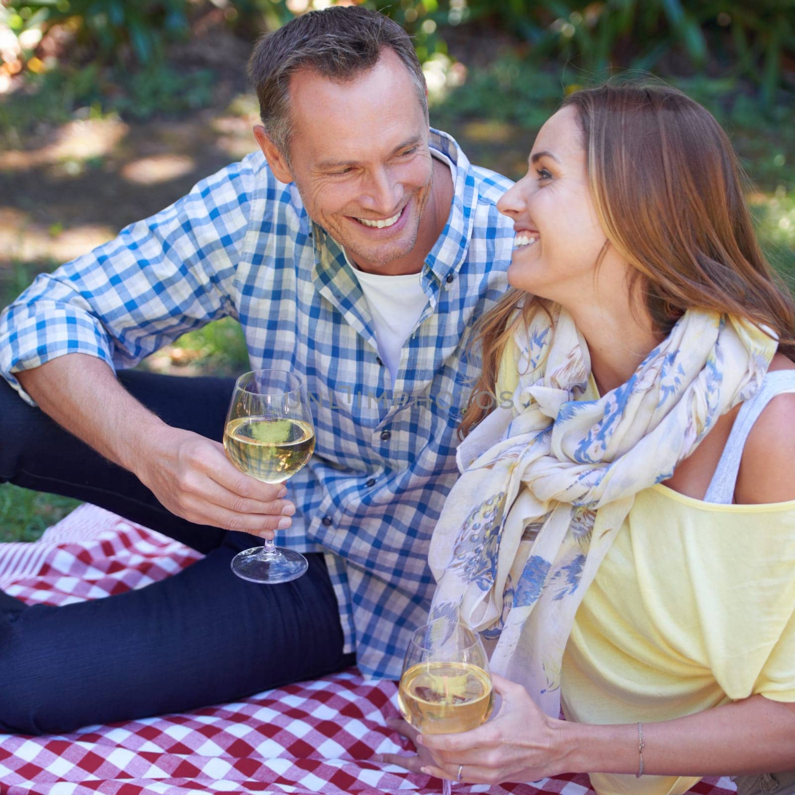 Couple, picnic and wine for bonding in outdoor nature, love and romance in relationship on weekend. Alcohol, conversation and people on date in countryside, adventure and forest for happy on vacation by YuriArcurs