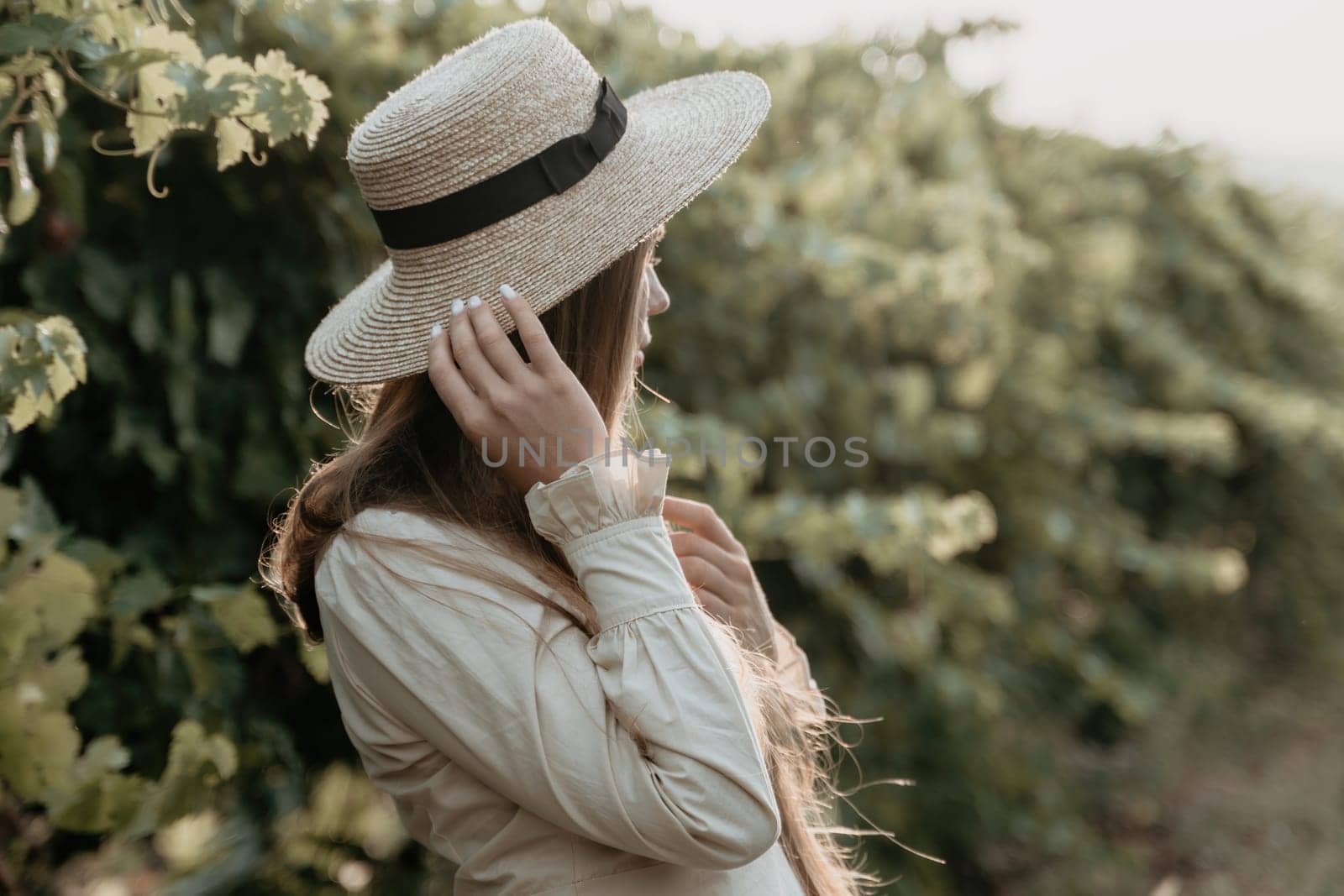Woman at autumn winery. Portrait of happy woman holding glass of wine and enjoying in vineyard. Elegant young lady in hat toasting with wineglass smiling cheerfully enjoying her stay at vineyard