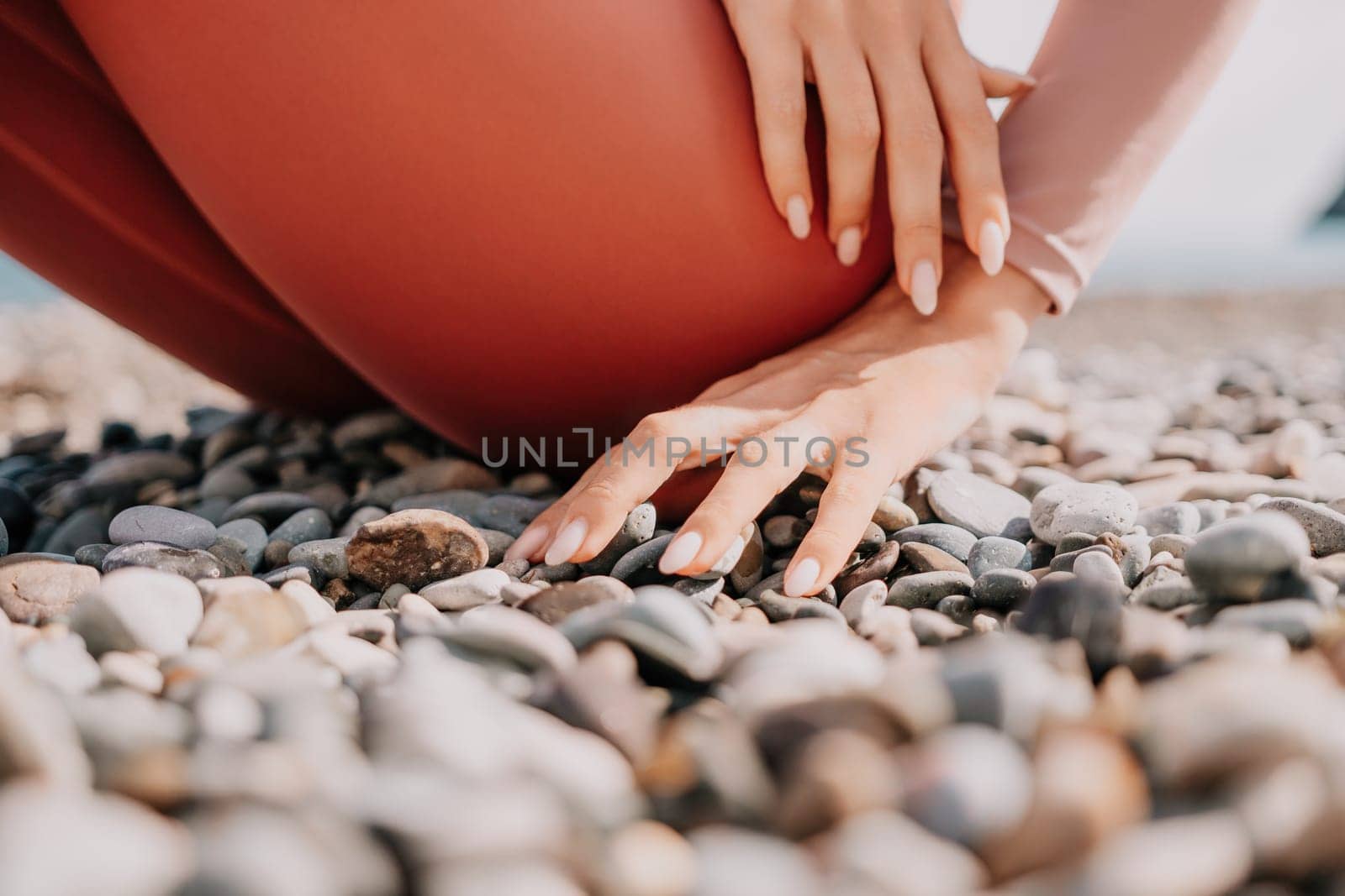 Middle aged well looking woman with black hair, fitness instructor in leggings and tops doing stretching and pilates on yoga mat near the sea. Female fitness yoga routine concept. Healthy lifestyle by panophotograph