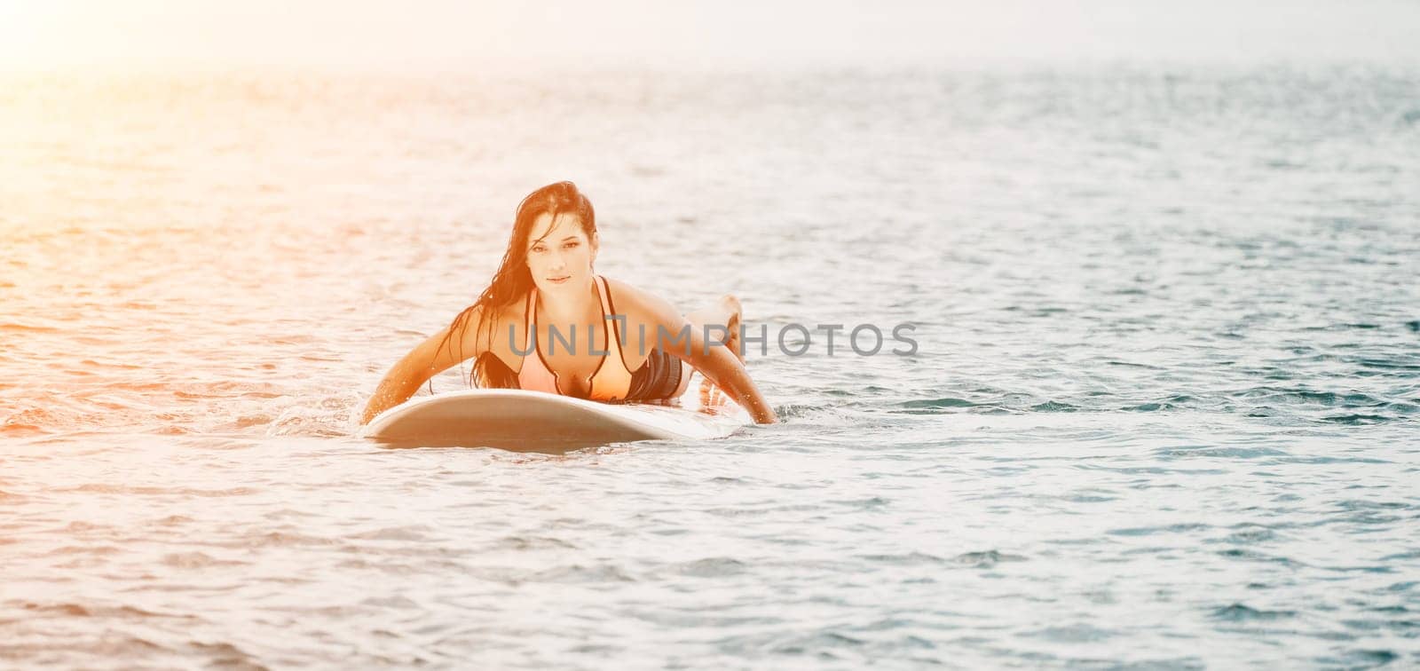 Sea woman sup. Silhouette of happy young woman in pink bikini, surfing on SUP board, confident paddling through water surface. Idyllic sunset. Active lifestyle at sea or river. by panophotograph
