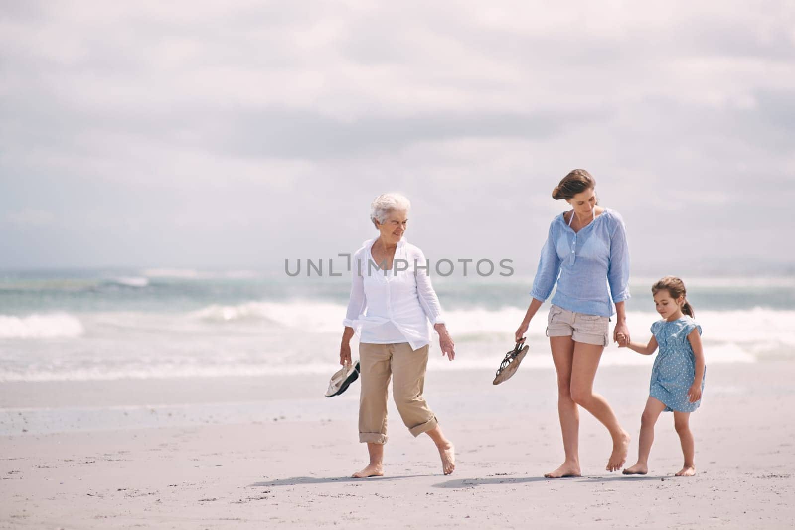 Mother, child and grandmother on beach holding hands for walking explore for holiday, vacation or environment. Family, woman and travel seaside in Australia for weekend bonding, peace or adventure by YuriArcurs