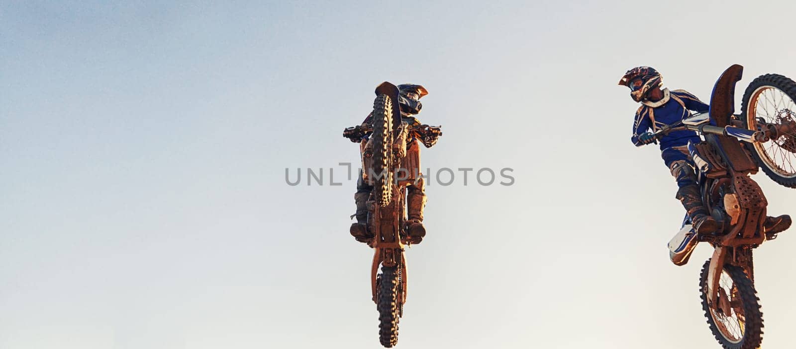 Sky, jump and men on motorcycle together for stunt at competition, training or challenge with banner mockup. Adventure, professional or athlete in air on motorbike for hobby, extreme sports or trick. by YuriArcurs