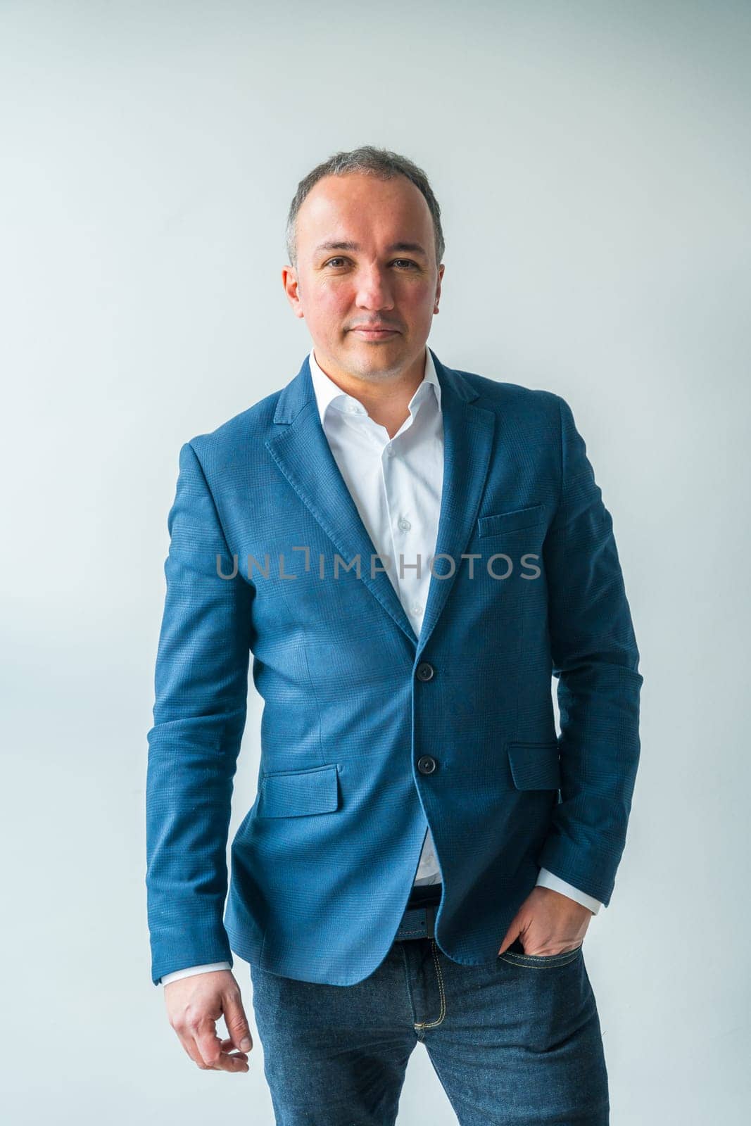 Vertical studio portrait with grey background of a businessman in casual elegant clothes standing