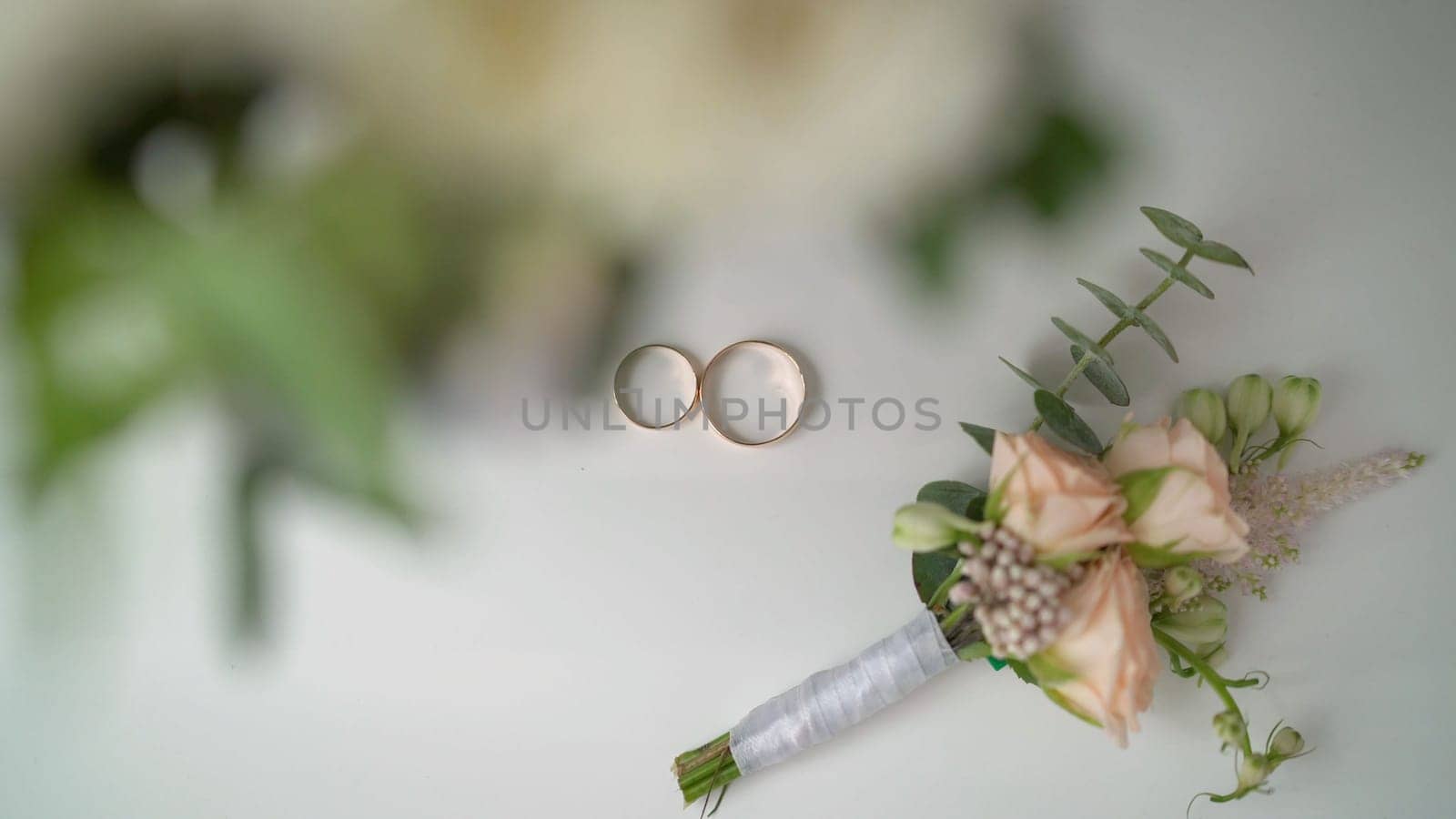 Wedding rings and boutonniere. Wedding boutonniere and wedding rings on brown cloth