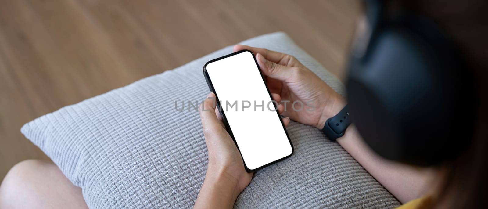 Mockup smartphone of a woman holding mobile phone with blank white screen while sitting listen to music at home by nateemee
