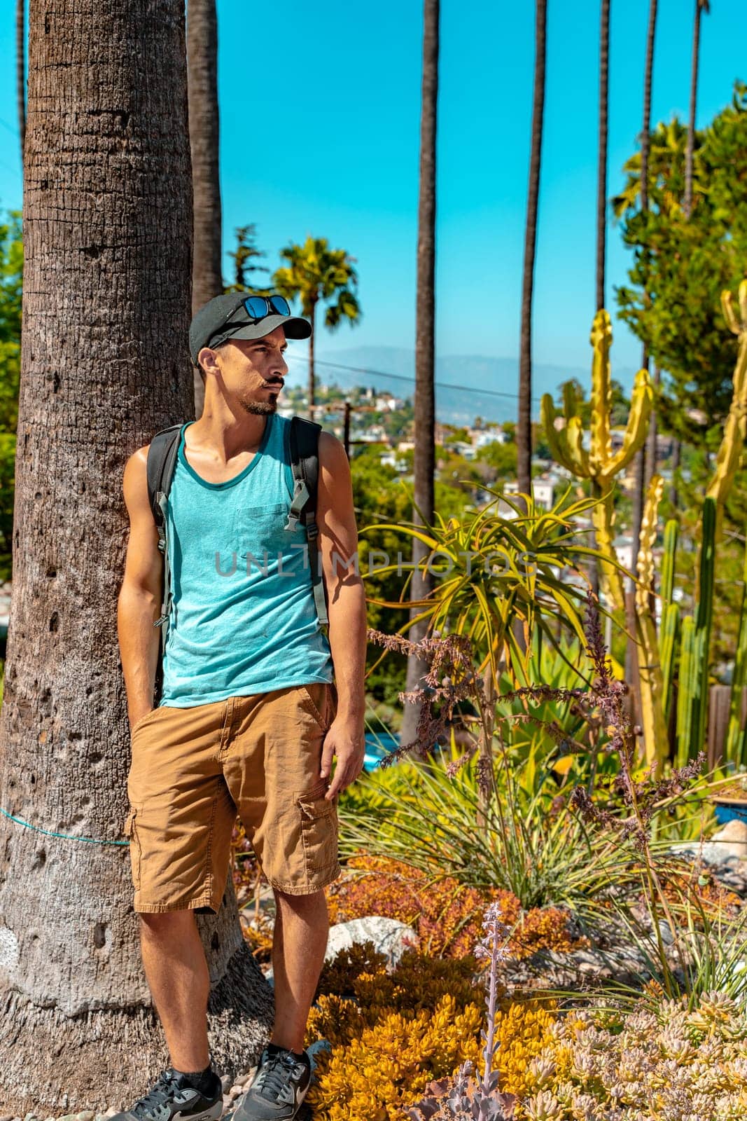 Portrait of stylish student in California with palm trees in the background during a sunny colorful day. High quality photo