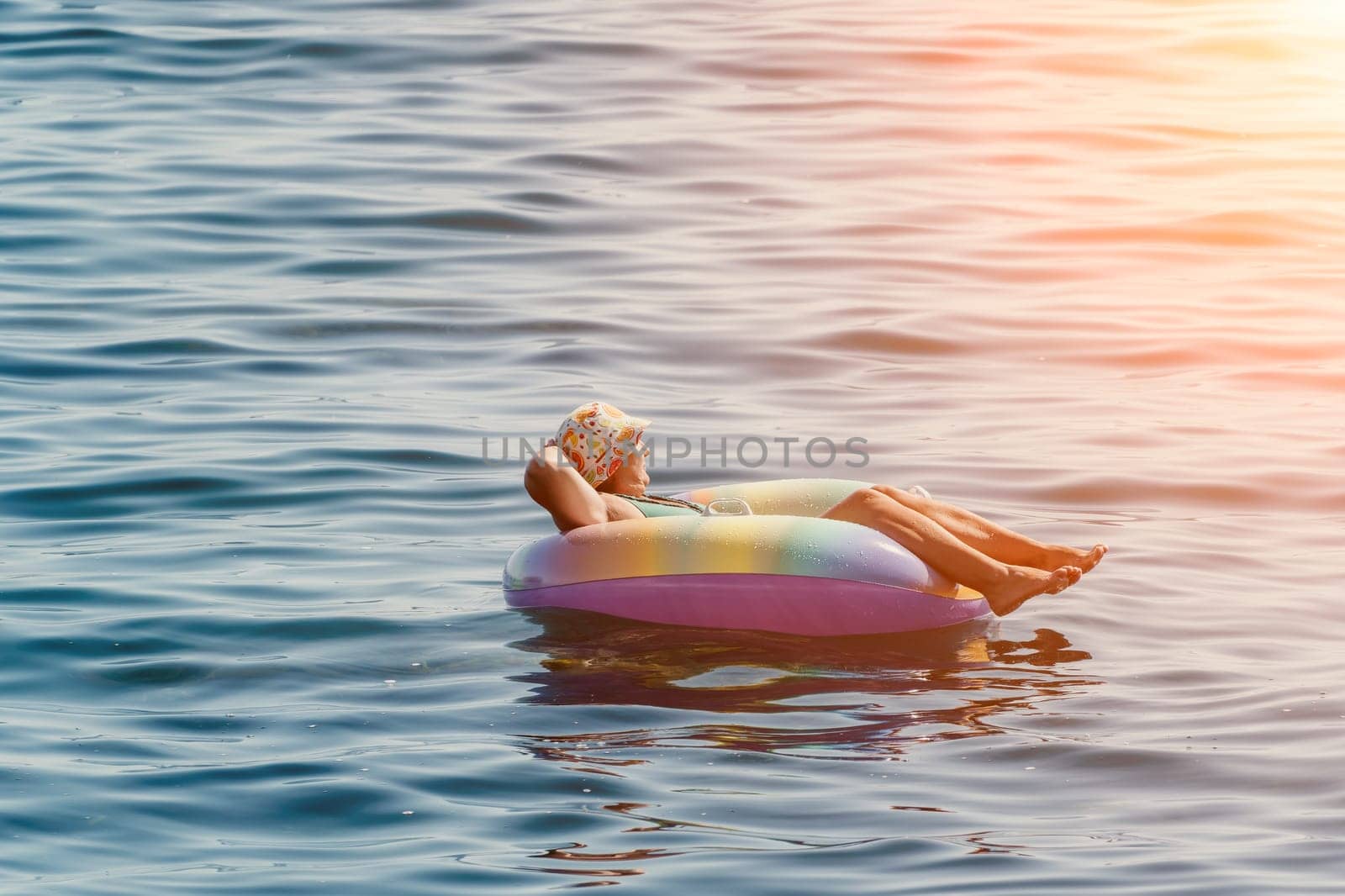 Summer Vacation Woman in hat floats on an inflatable donut mattress, a water toy swim ring. Unrecognizable young woman relaxing and enjoying family summer travel holidays vacation on the sea