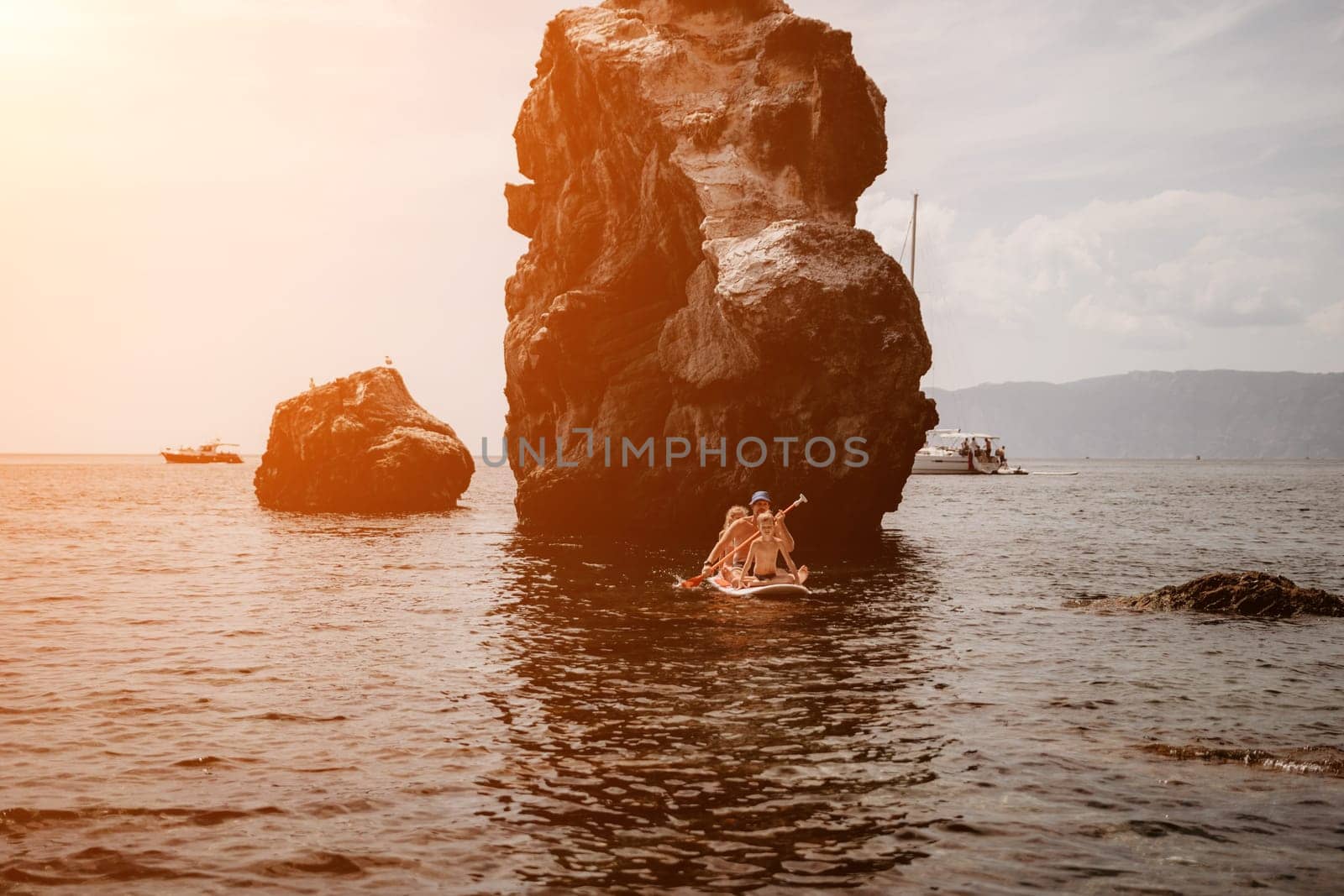 Family sea sup. Young happy father with his son and daughter Floating on a SUP board, paddling in blue sea water. summer vacation and Dad and Son Daughter concept. by panophotograph