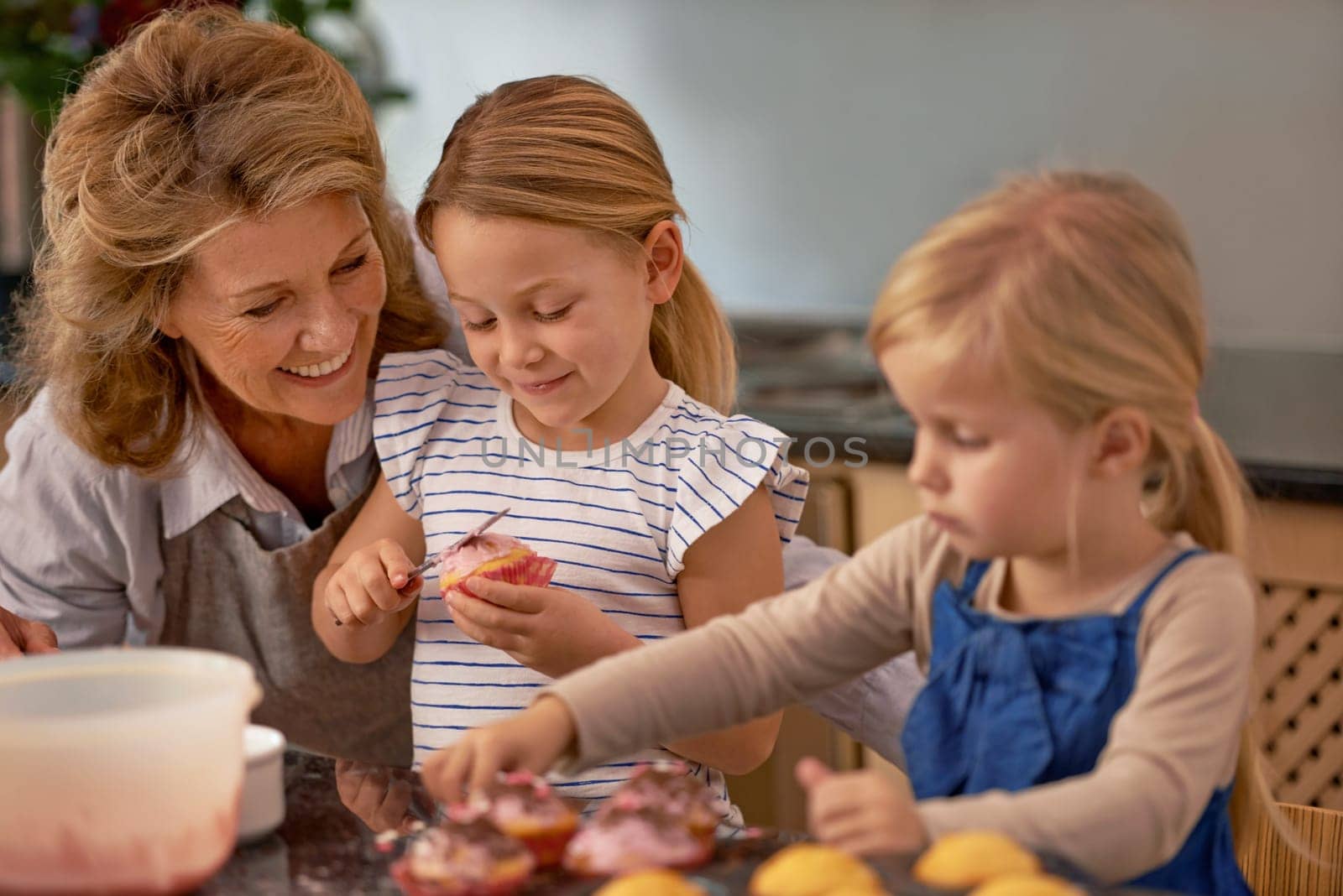 Grandmother, children and baking cupcake or teaching with icing decorations or learning creativity, bonding or teamwork. Woman, siblings and sweet dessert or helping with ingredients, snack or fun.