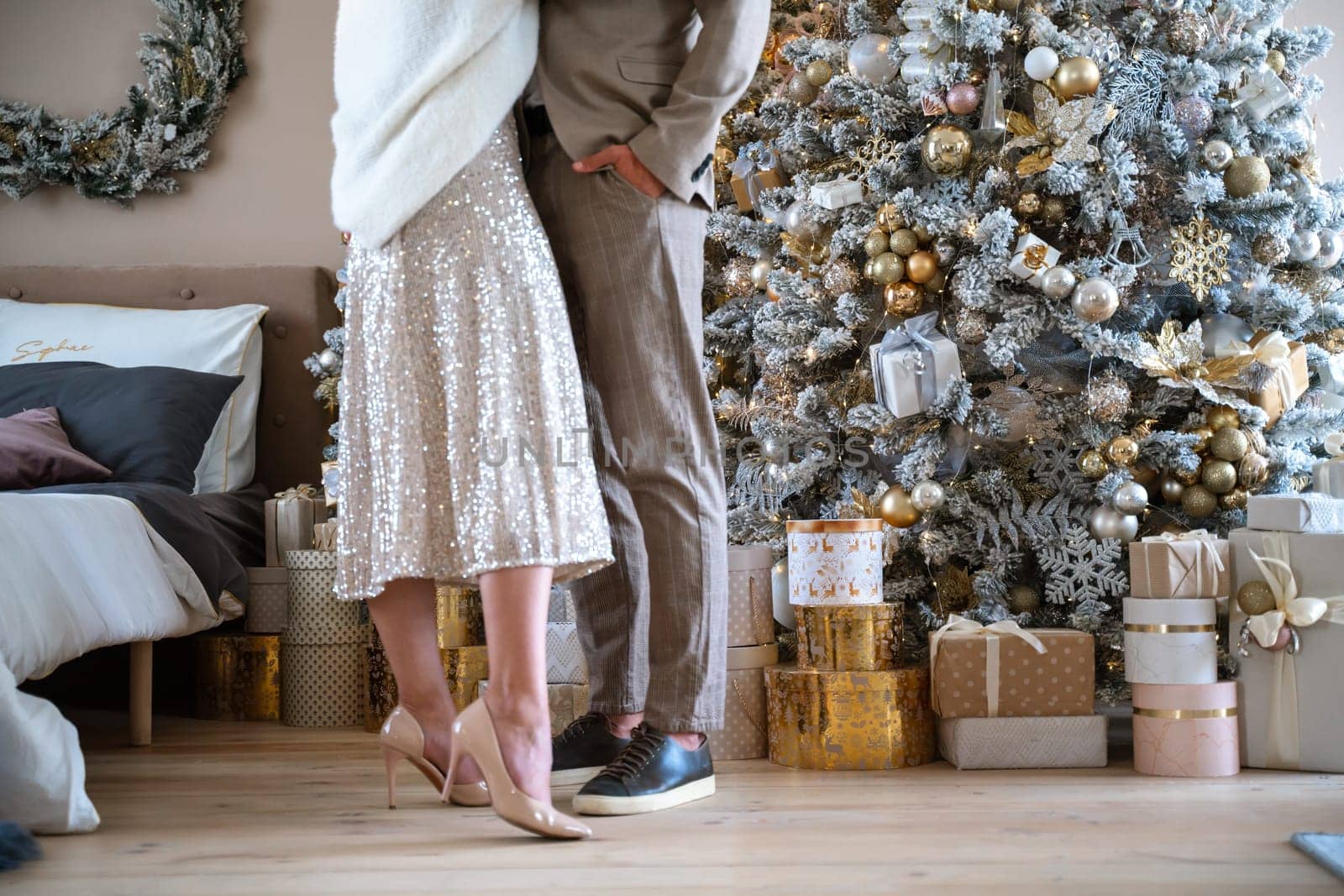 Romantic couple standing near Christmas tree at home and hugging.