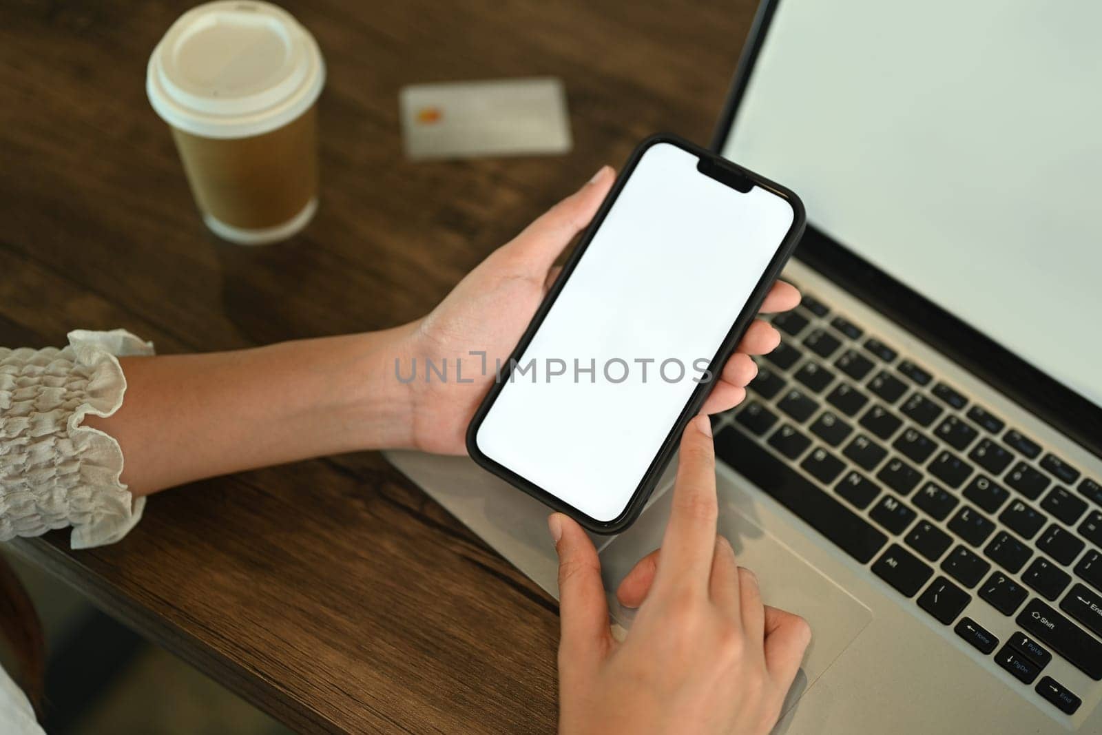 Closeup view businesswoman using smartphone at working desk during coffee break.