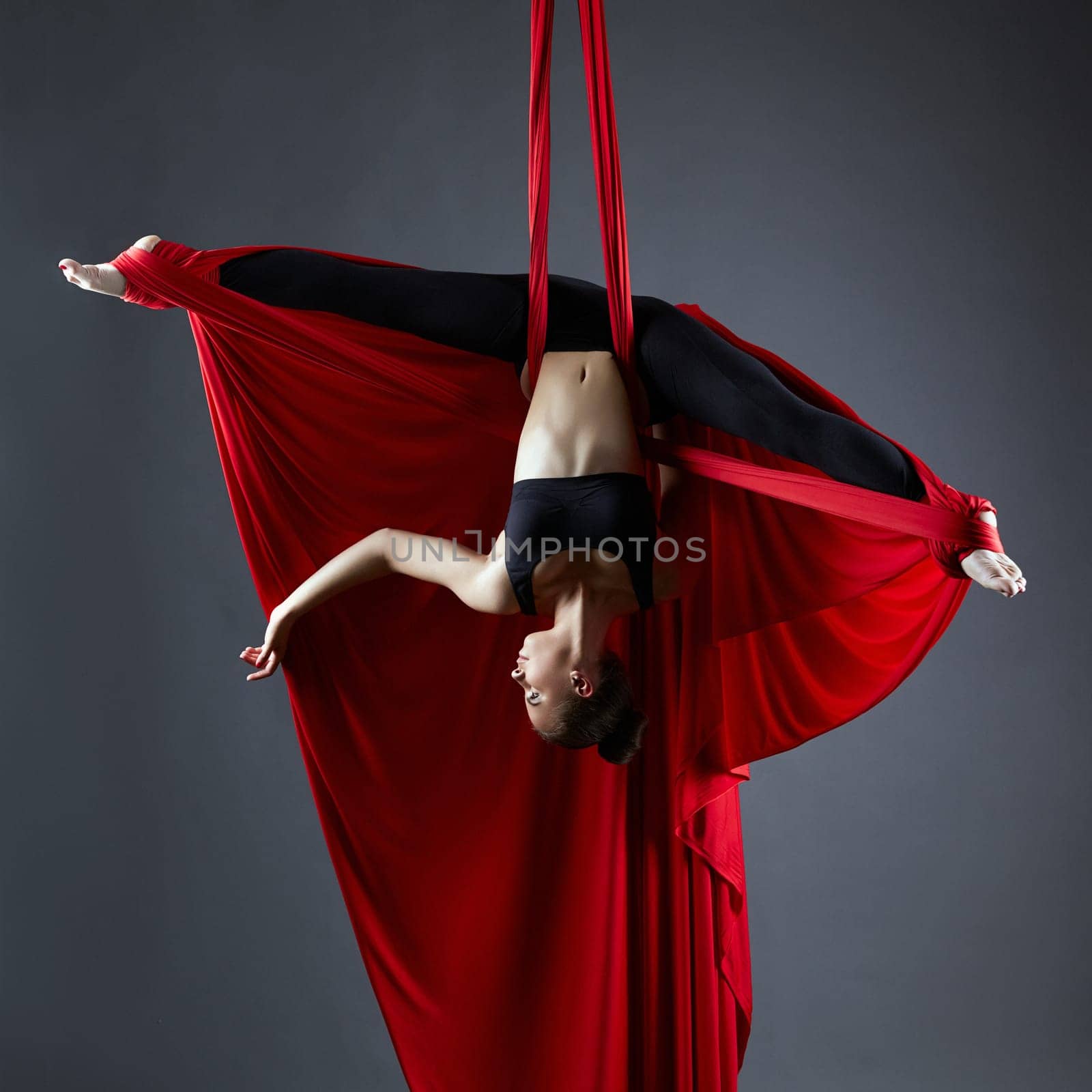 Graceful dancer on aerial silks posing upside down by rivertime