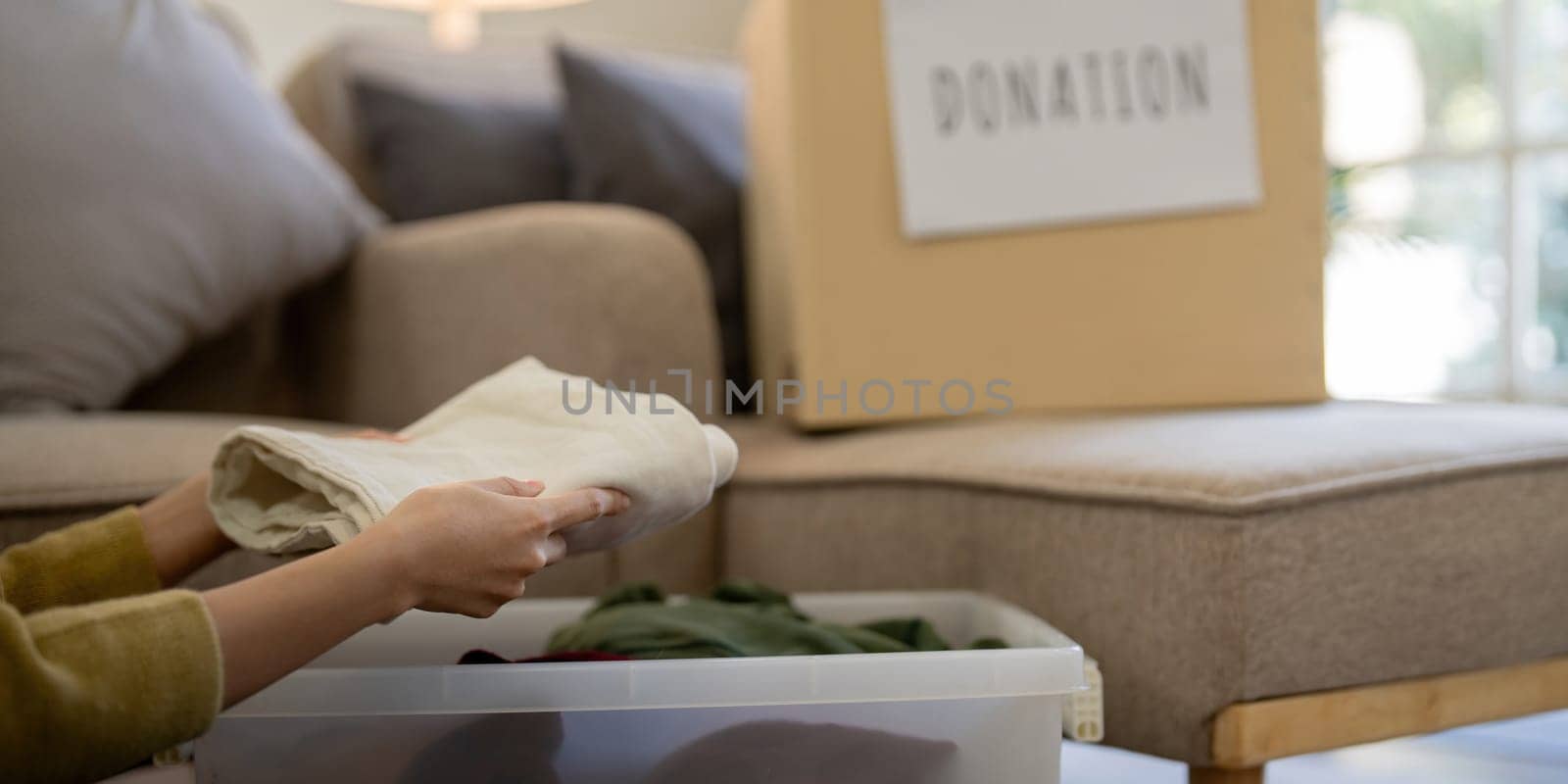 Donation, asian young woman sitting pack object at home, putting on stuff into donate box with second hand clothes, charity helping and needy people. Reuse recycle by nateemee