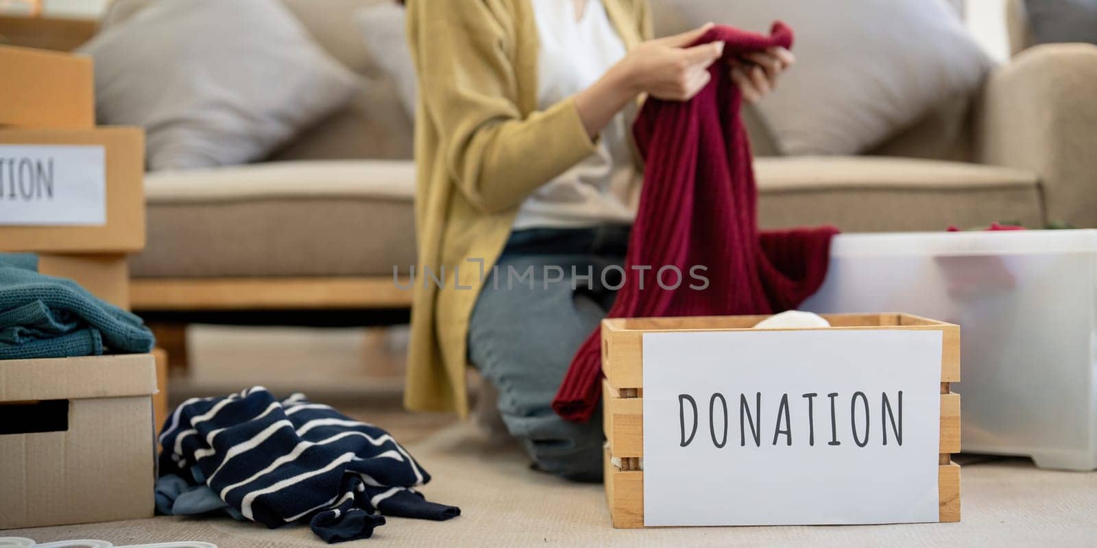 Donation, asian young woman sitting pack object at home, putting on stuff into donate box with second hand clothes, charity helping and needy people. Reuse recycle by nateemee