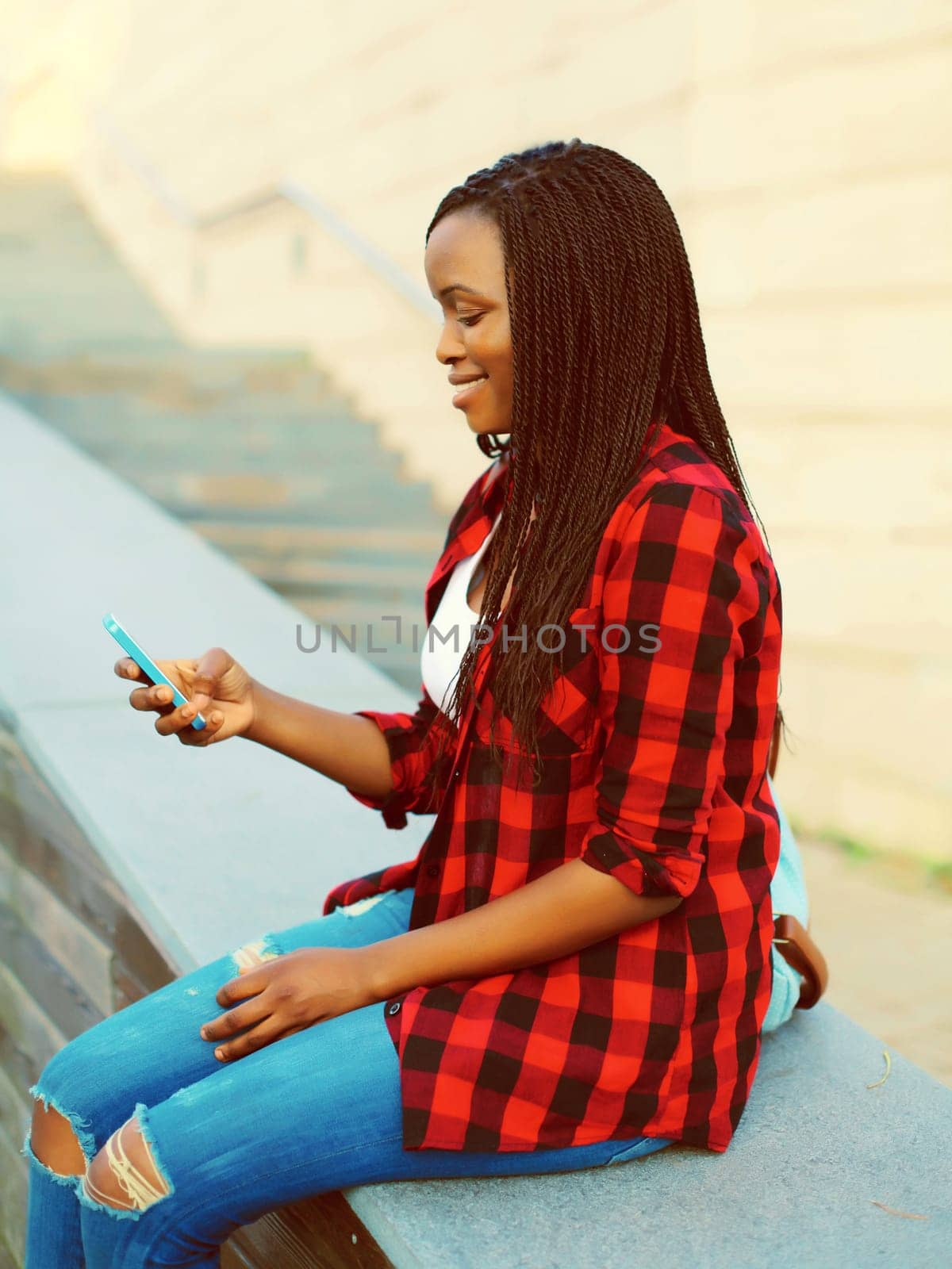 Happy young smiling african woman with smartphone student in the city by Rohappy