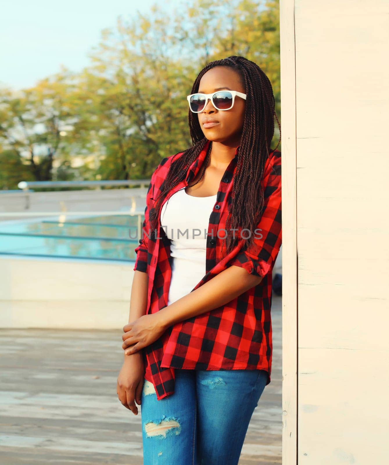 Portrait of beautiful young african woman posing wearing casual, sunglasses in the city