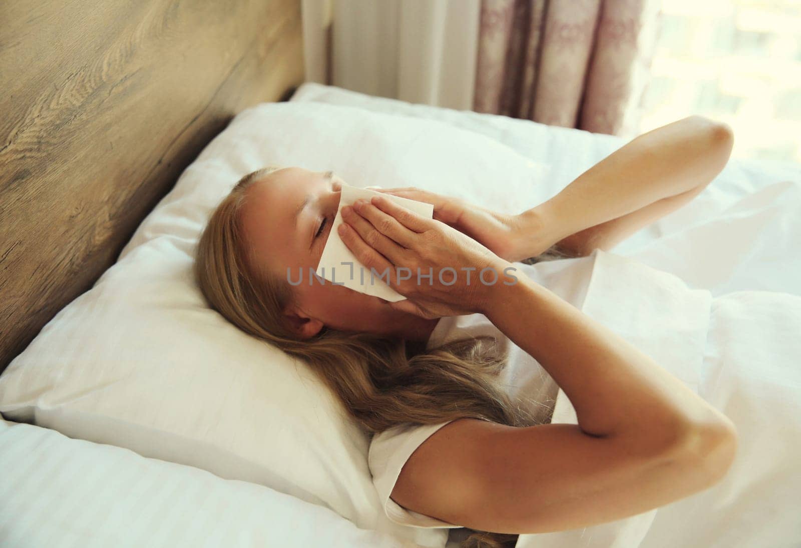 Sick upset woman sneezing blow nose using tissue lying in bed at home