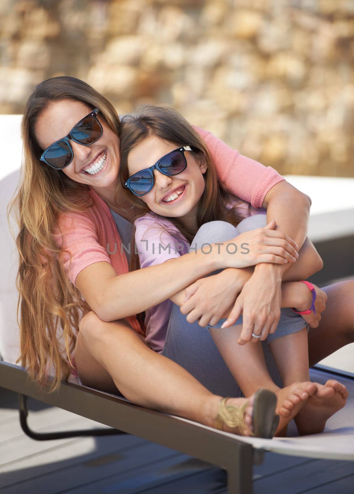 Portrait, smile and mother on vacation with daughter outdoor in sunglasses for summer, travel or holiday. Family, love and mom hugging girl child on poolside deck chair for bonding, trip or getaway.