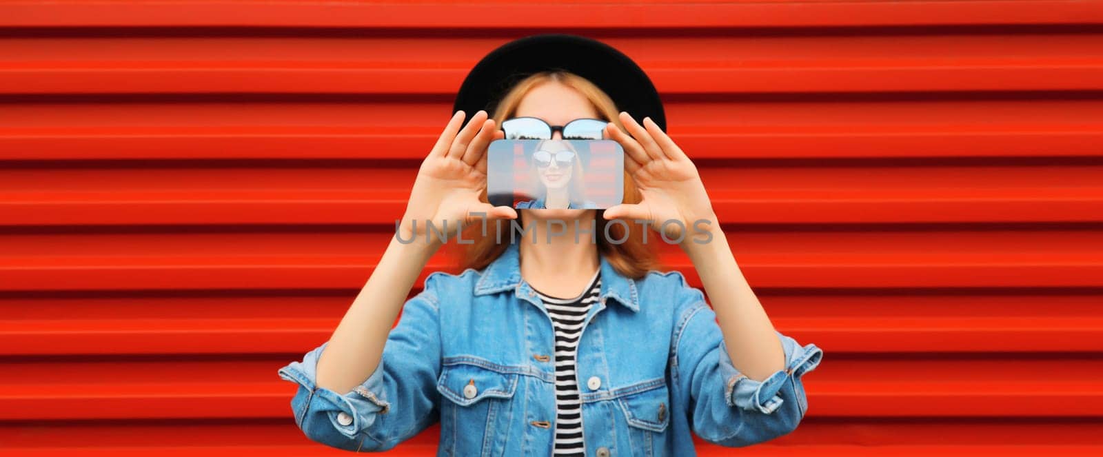 Close up of modern young woman stretching her hands taking selfie with smartphone on red background