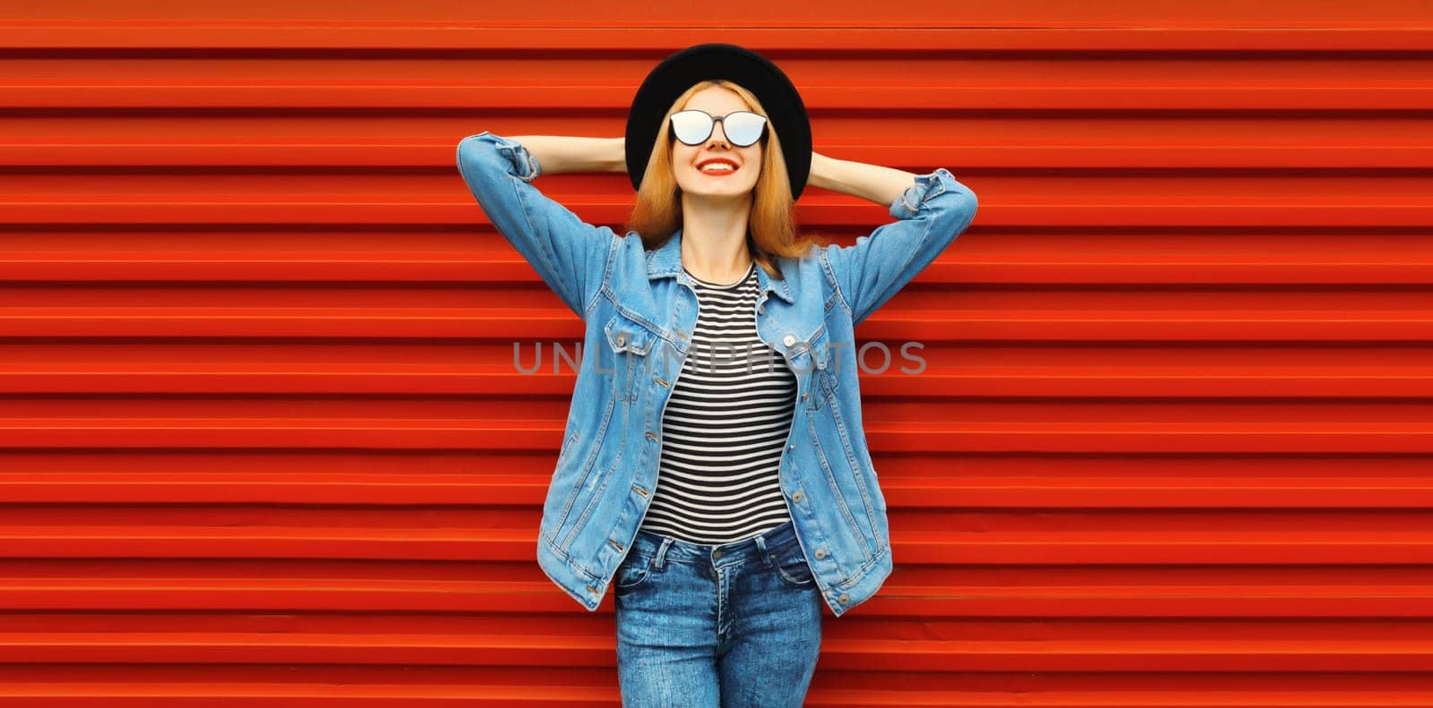 Portrait of stylish modern smiling young woman wearing in jacket, black hat on red background by Rohappy