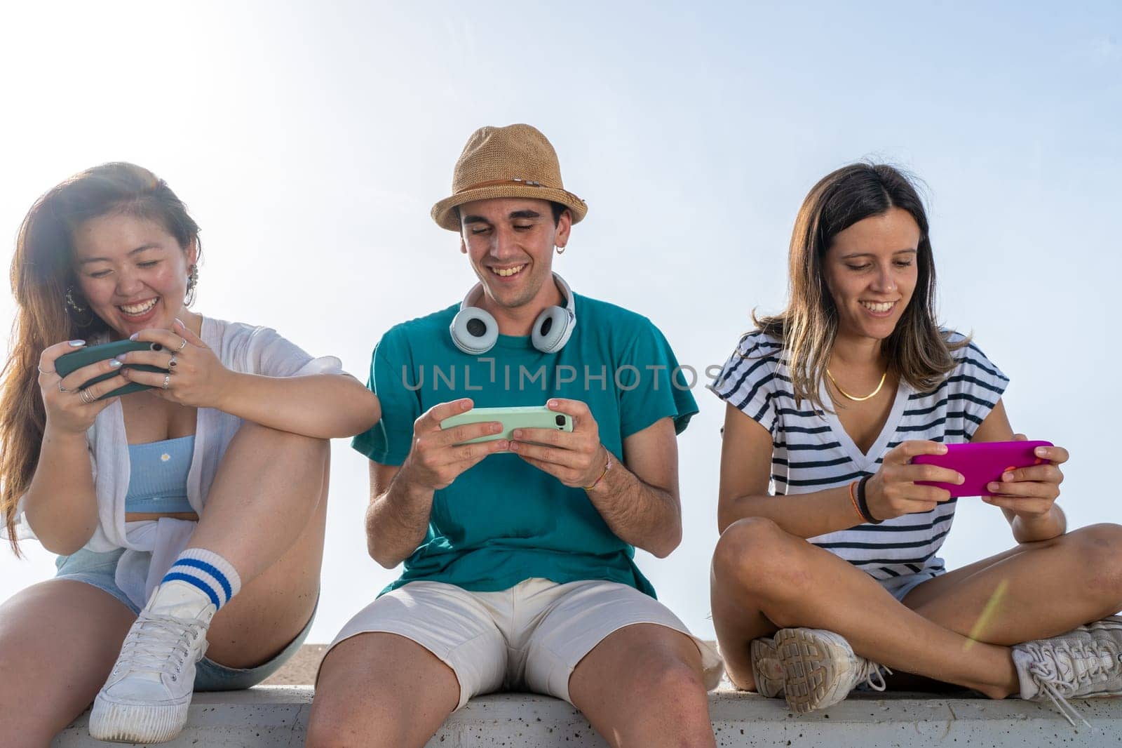 Multicultural group of trendy young friends having fun using smartphones and social media. Mobile games. High quality photo