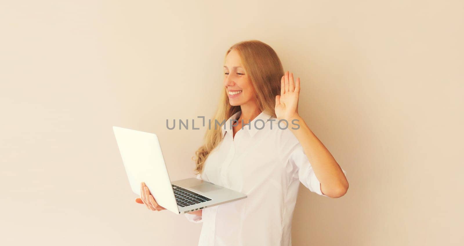 Happy caucasian middle-aged woman greets communicates with friends via video call on laptop at home