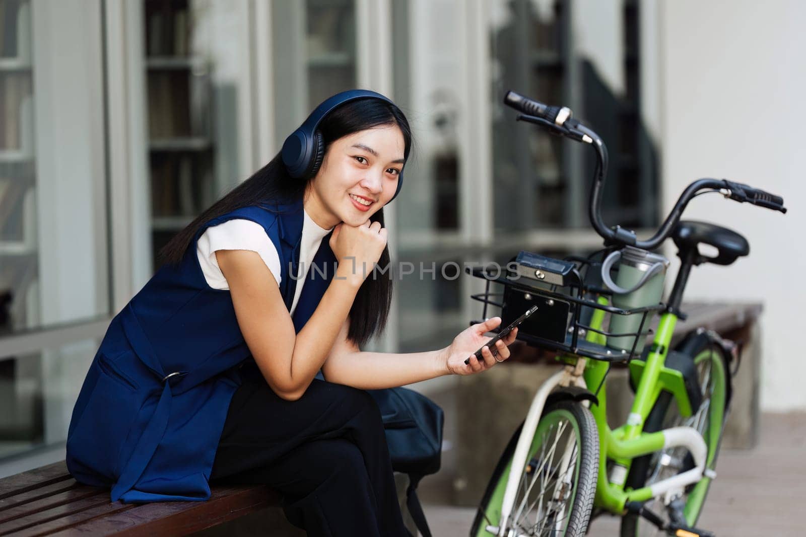 Asian young businesswoman bike to work for eco friendly green energy and use smart phone while commuting in city. Eco friendly.