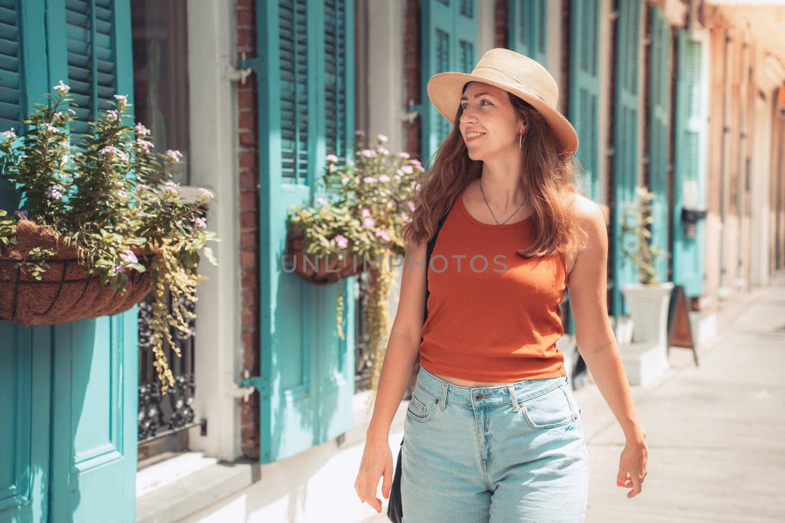 A woman in a sun hat strolls along the street in summer happy smiling. High quality photo