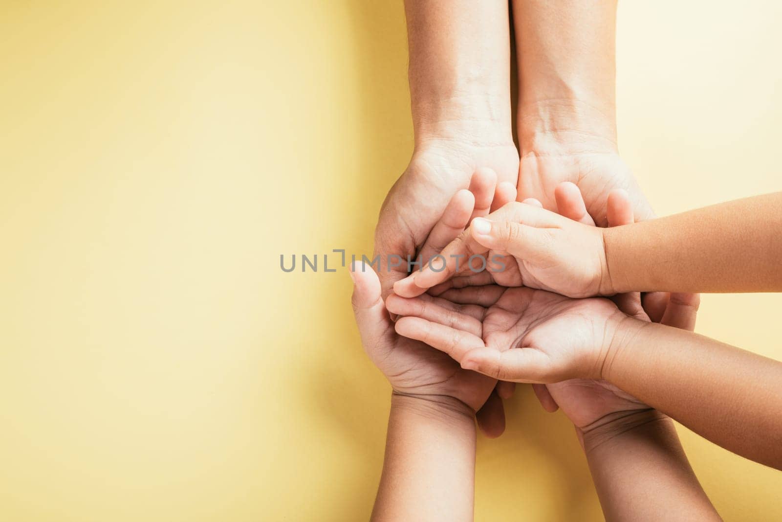 Symbol of support and love, Studio shot exhibits a top view of family hands stacked on an isolated background. Parents and kids hold an empty space for Family and Parents Day. by Sorapop