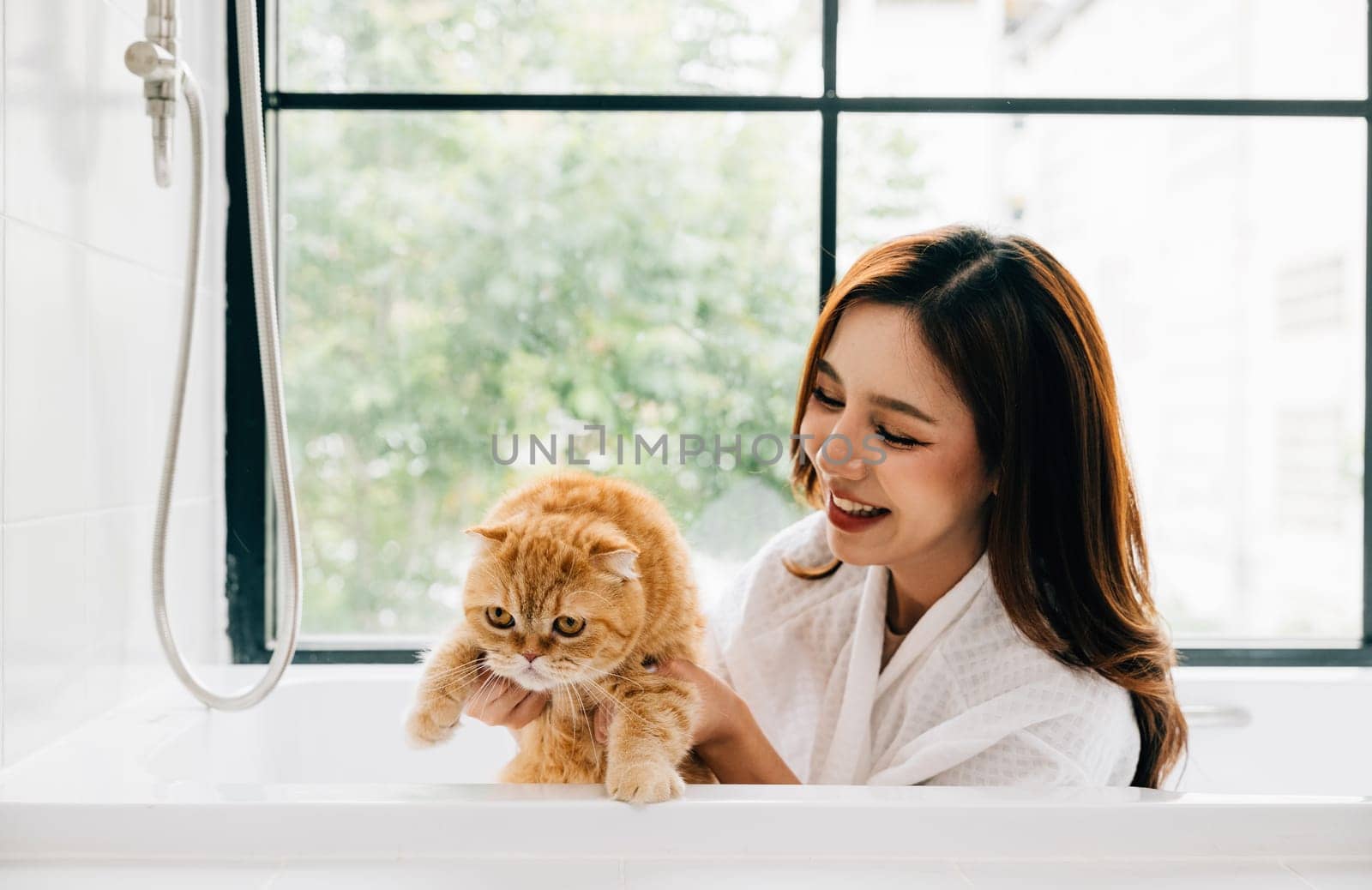 Indulging in a spa-like bath, a smiling woman shares a bathtub with her Scottish Fold cat, a heartwarming scene of relaxation and pet care. by Sorapop