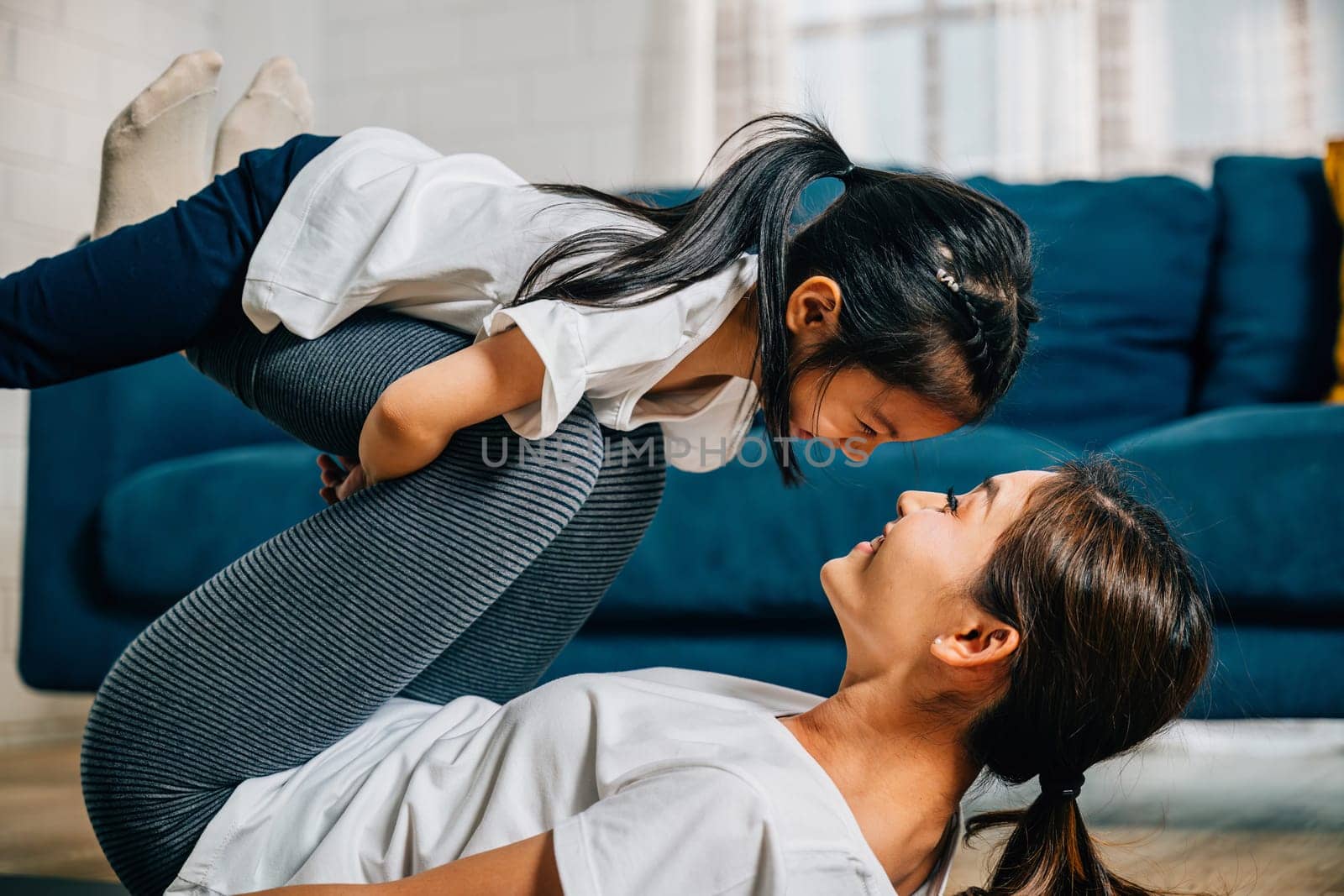 A mother and her child share a delightful family fitness moment playfully 'flying' like airplanes during their Pilates and yoga routine fostering trust harmony and happiness.