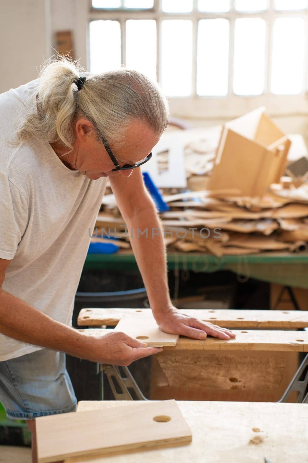 Professional elderly man carpenter artist working on wood using carpentry tools in the workshop by PaulCarr