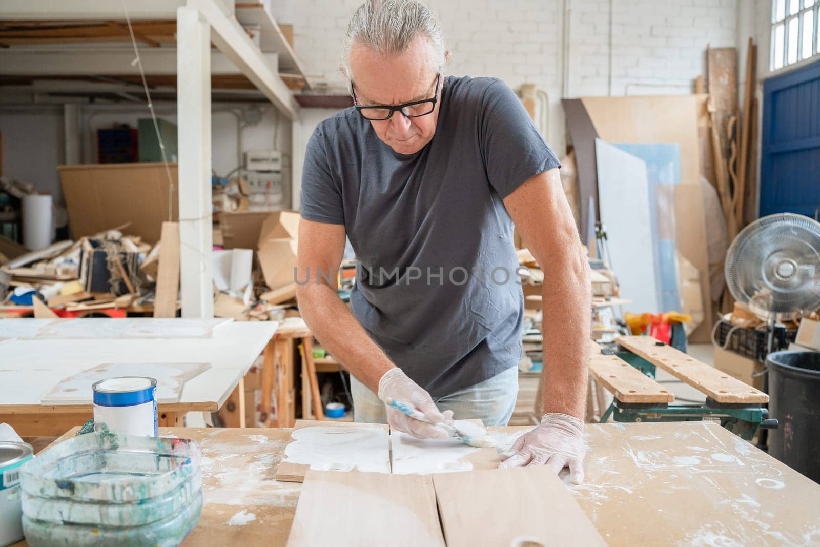 Senior artist working on wood craft at workshop painting wooden furniture. High quality photo