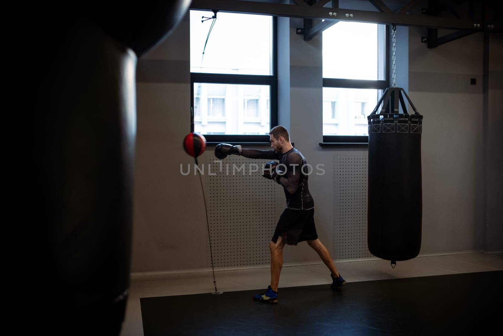 Focused boxer working on punches with double-end bag in gym by nazarovsergey