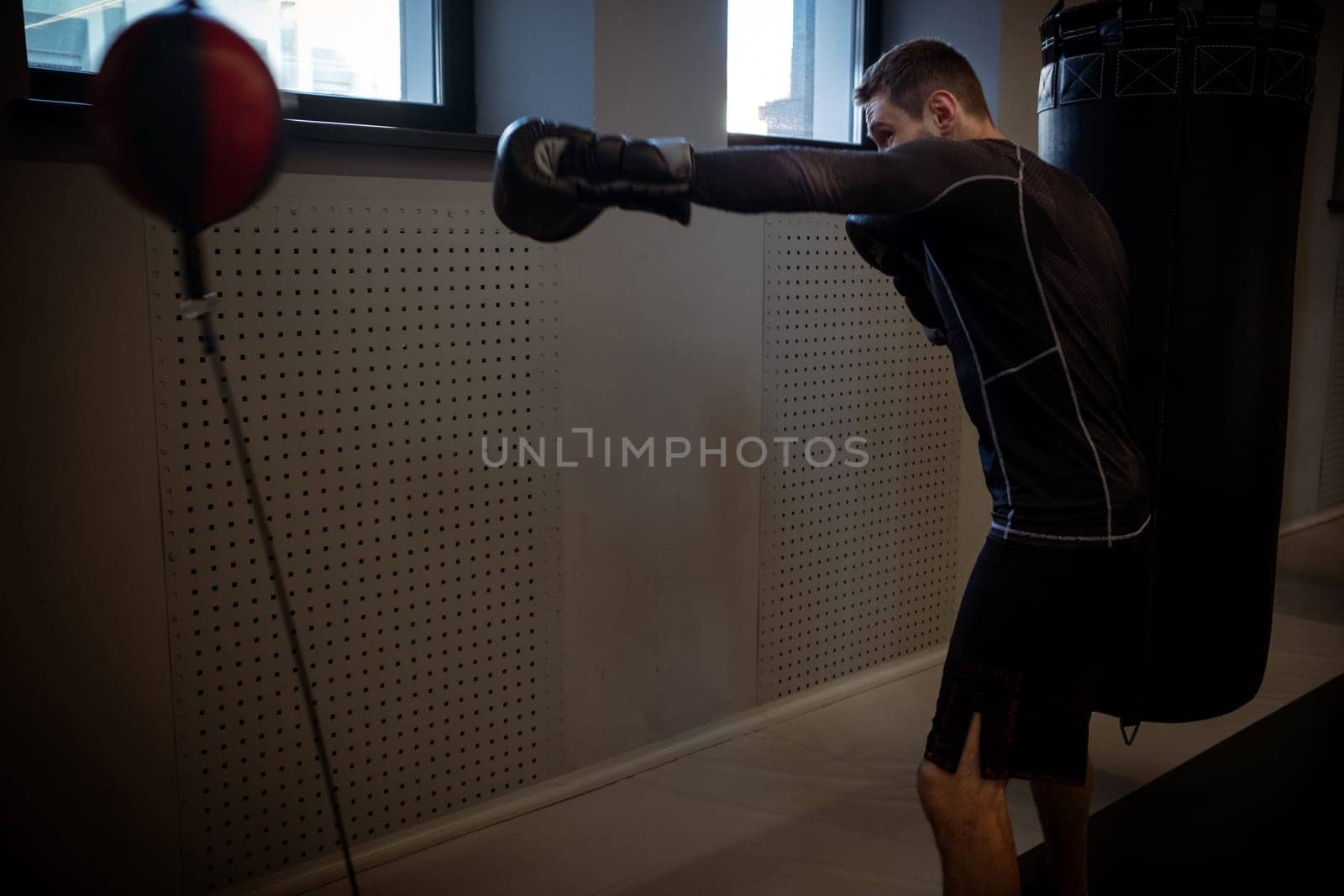 Dynamic scene capturing intense workout of motivated boxer practicing on floor-to-ceiling bag in gym, enhancing punch precision, speed and coordination in gym environment