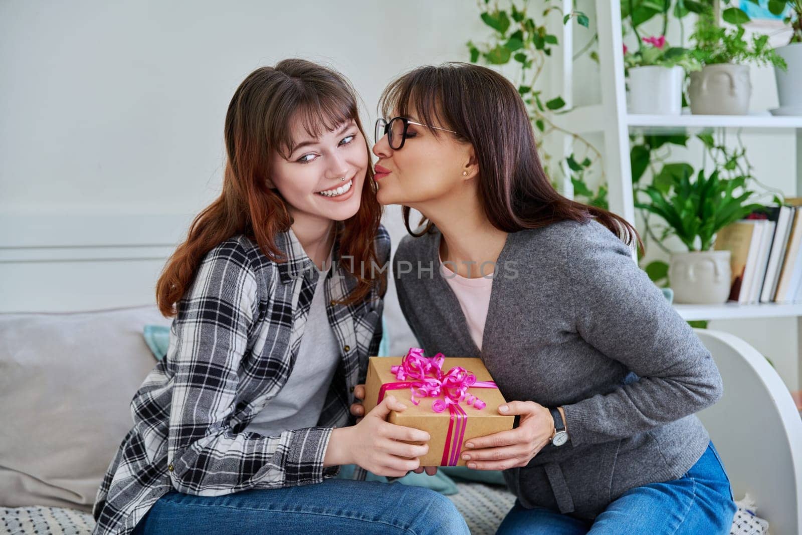 Teenage daughter congratulating middle aged mother with gift by VH-studio