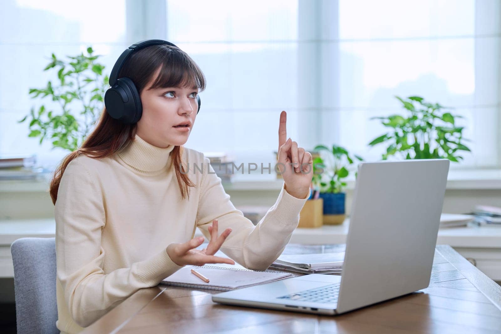 Teenage girl college student in headphones having video conference chat online meeting lesson webinar on computer laptop screen, sitting at desk at home. E-learning, education, technology, knowledge