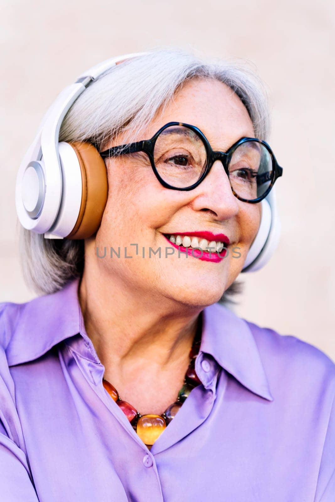 beautiful senior woman smiling happy listening to music on her headphones, concept of elderly people leisure and active lifestyle