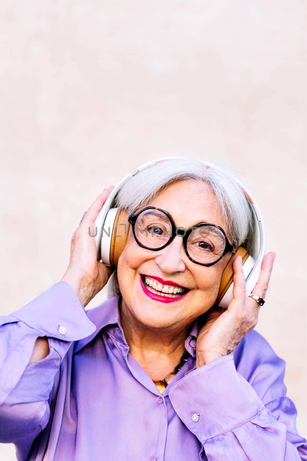 funny senior woman smiling happy listening to music on her headphones, concept of elderly people leisure and active lifestyle, copy space for text