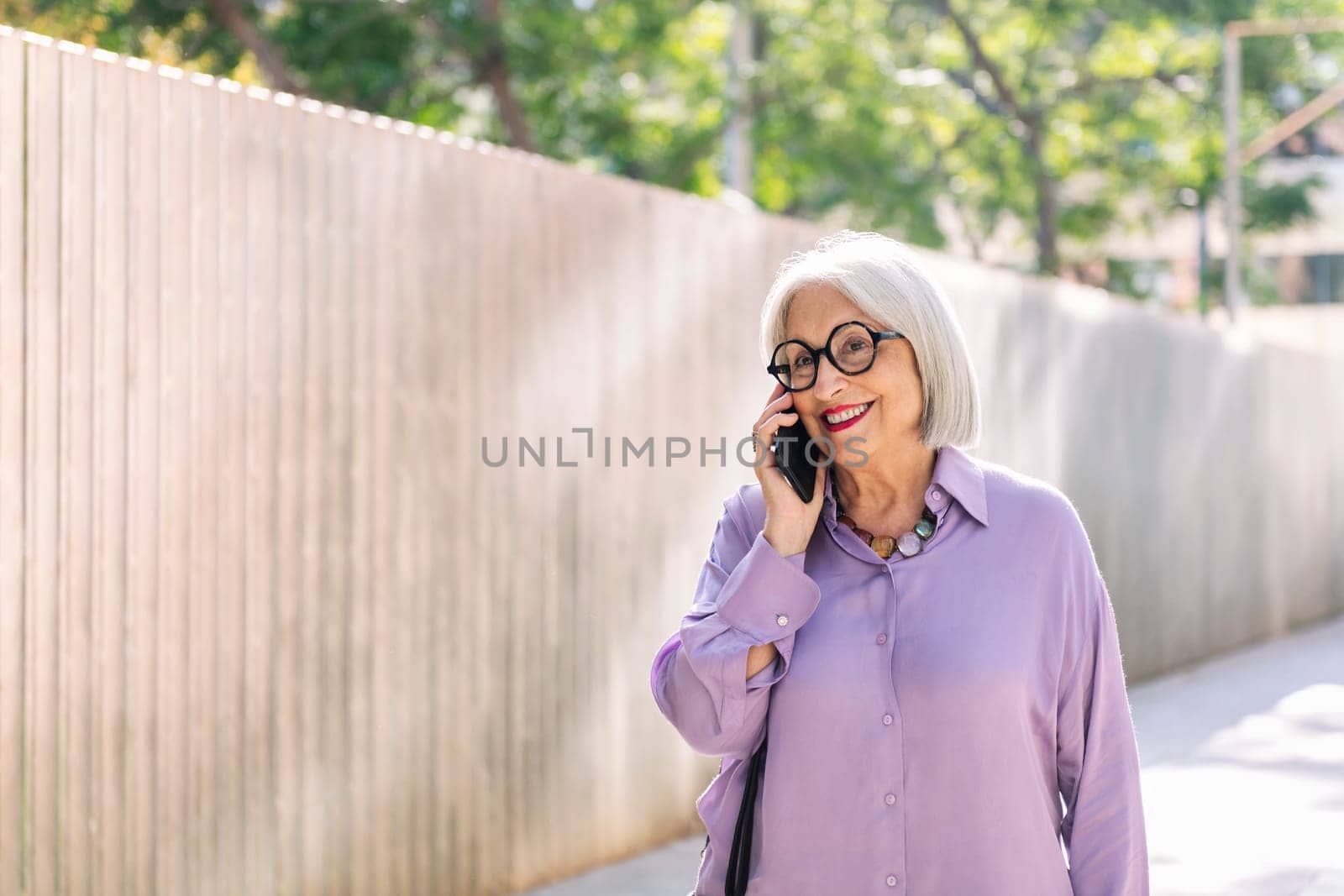 senior woman walking and talking on the phone by raulmelldo